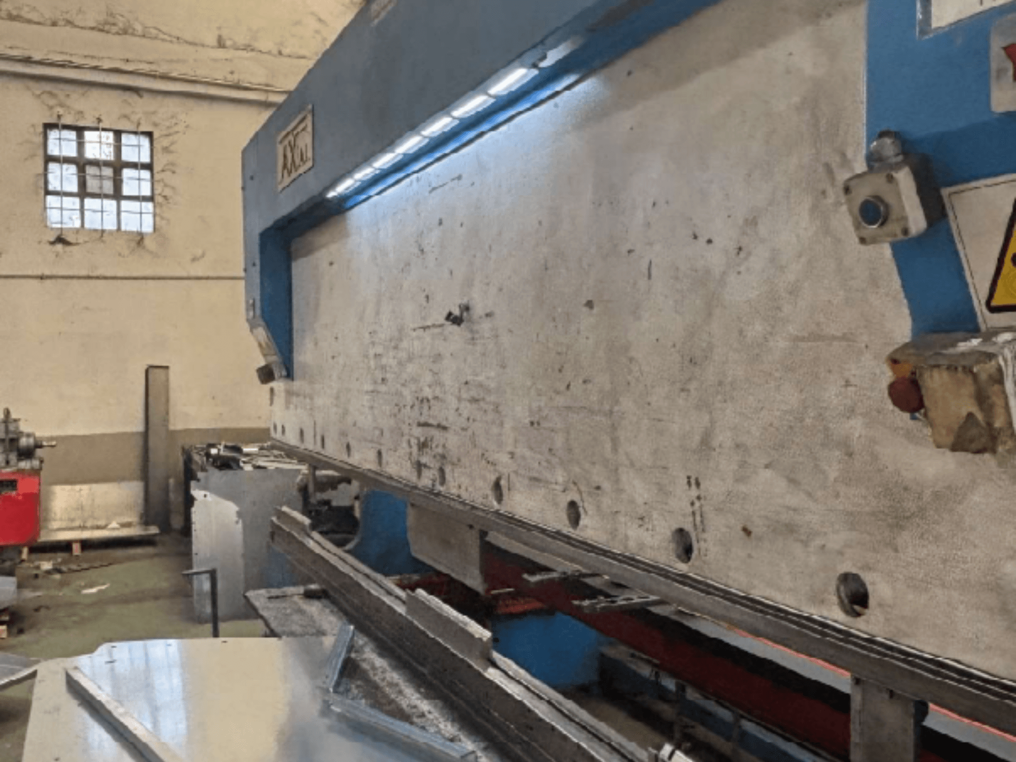 Système de manutention de palettes Axial PHS-W-124 dans un atelier, vue latérale montrant la surface de travail et les détails du panneau de commande.