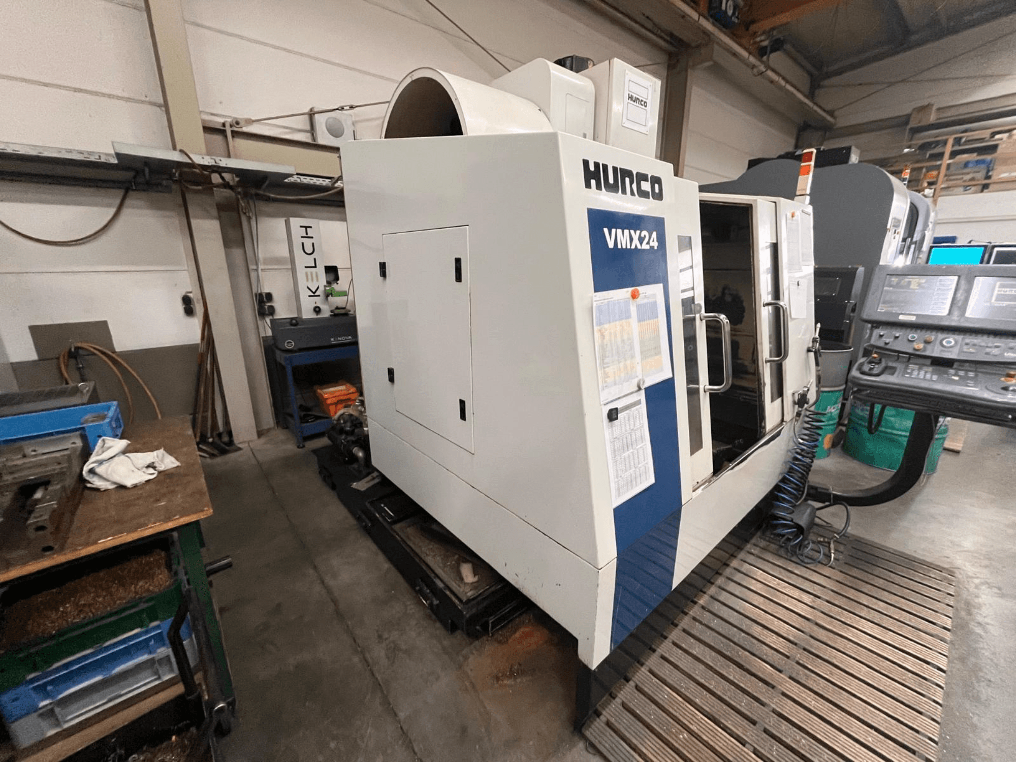 Machine CNC Hurco VMX24 dans un atelier, vue de face ; elle comporte un panneau de commande et une porte d'accès ouverte.