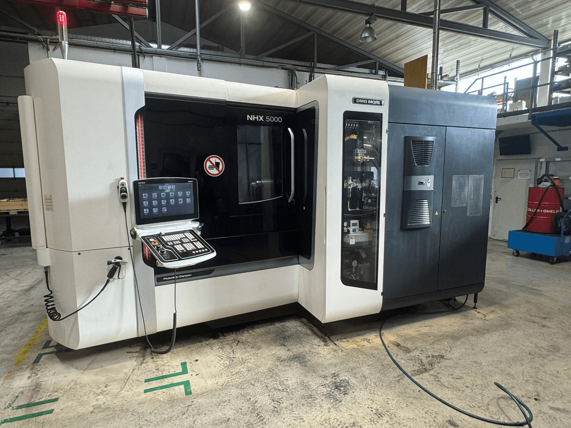 Centre d'usinage horizontal DMG MORI NHX 5000, vue de face avec panneau de commande visible et indicateurs de sécurité.