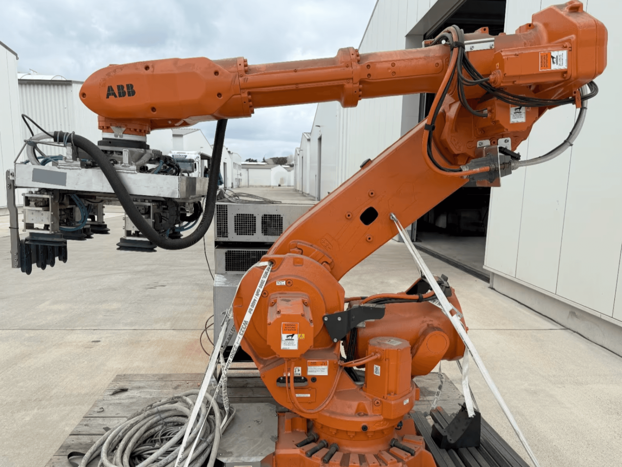 Bras robotique ABB RB 6600-130/3.2 en vue latérale, avec un bras robotique orange doté d'une pince et d'un câblage visible.