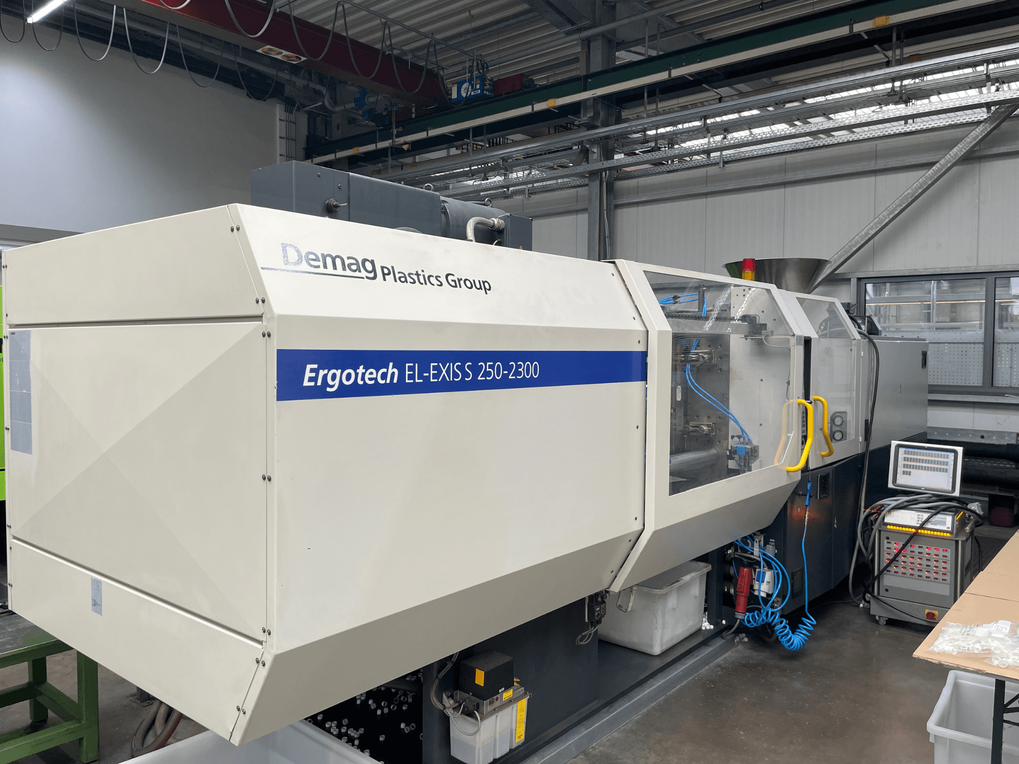 Machine de moulage par injection Demag Ergotech EL-EXIS S 250-2300, vue latérale, montrant le panneau de commande et le système d'alimentation.