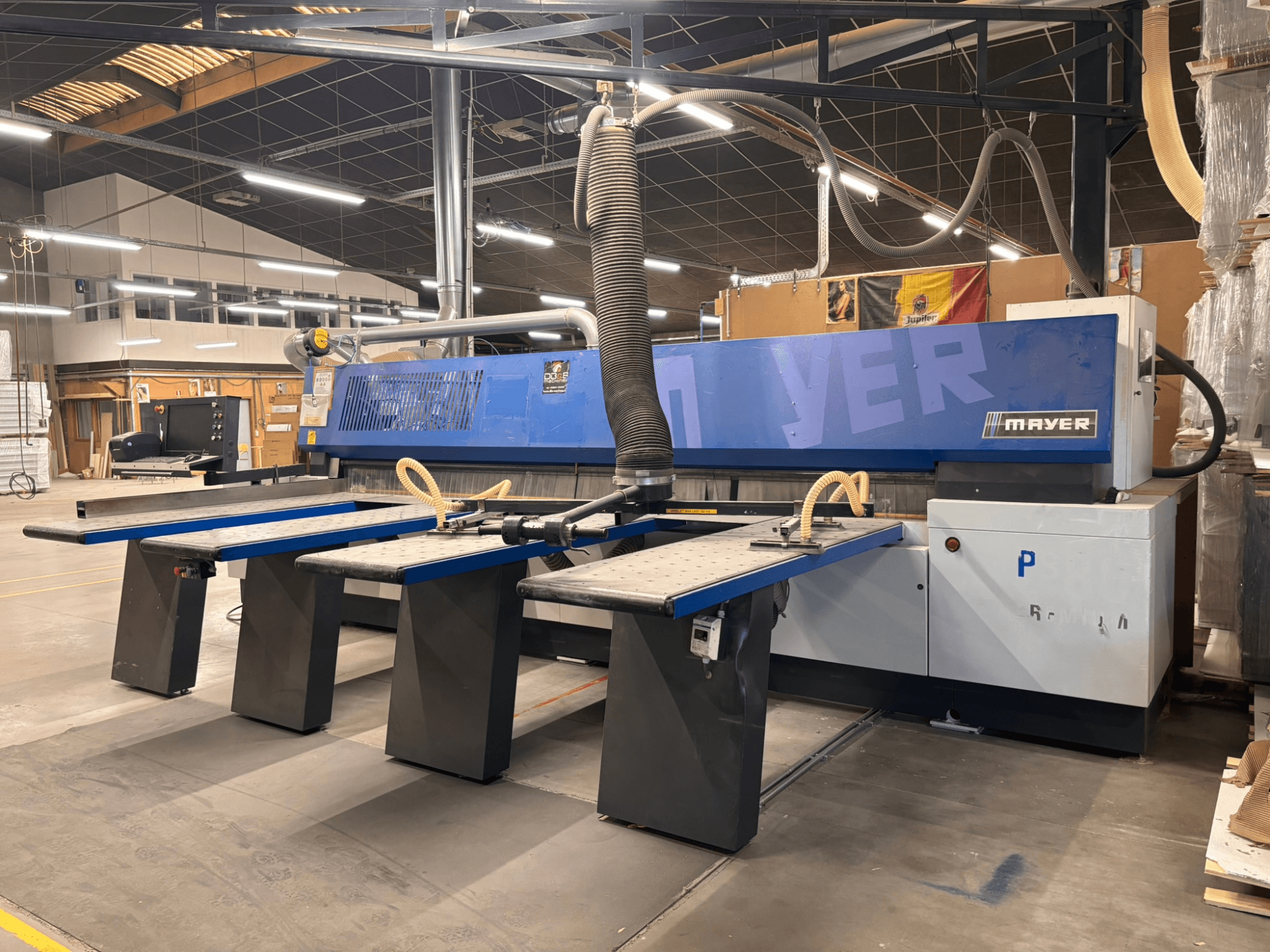 Machine CNC Mayer avec panneaux bleus, vue de face ; comprend plusieurs tables de travail et un système d'extraction des poussières pour le travail du bois.