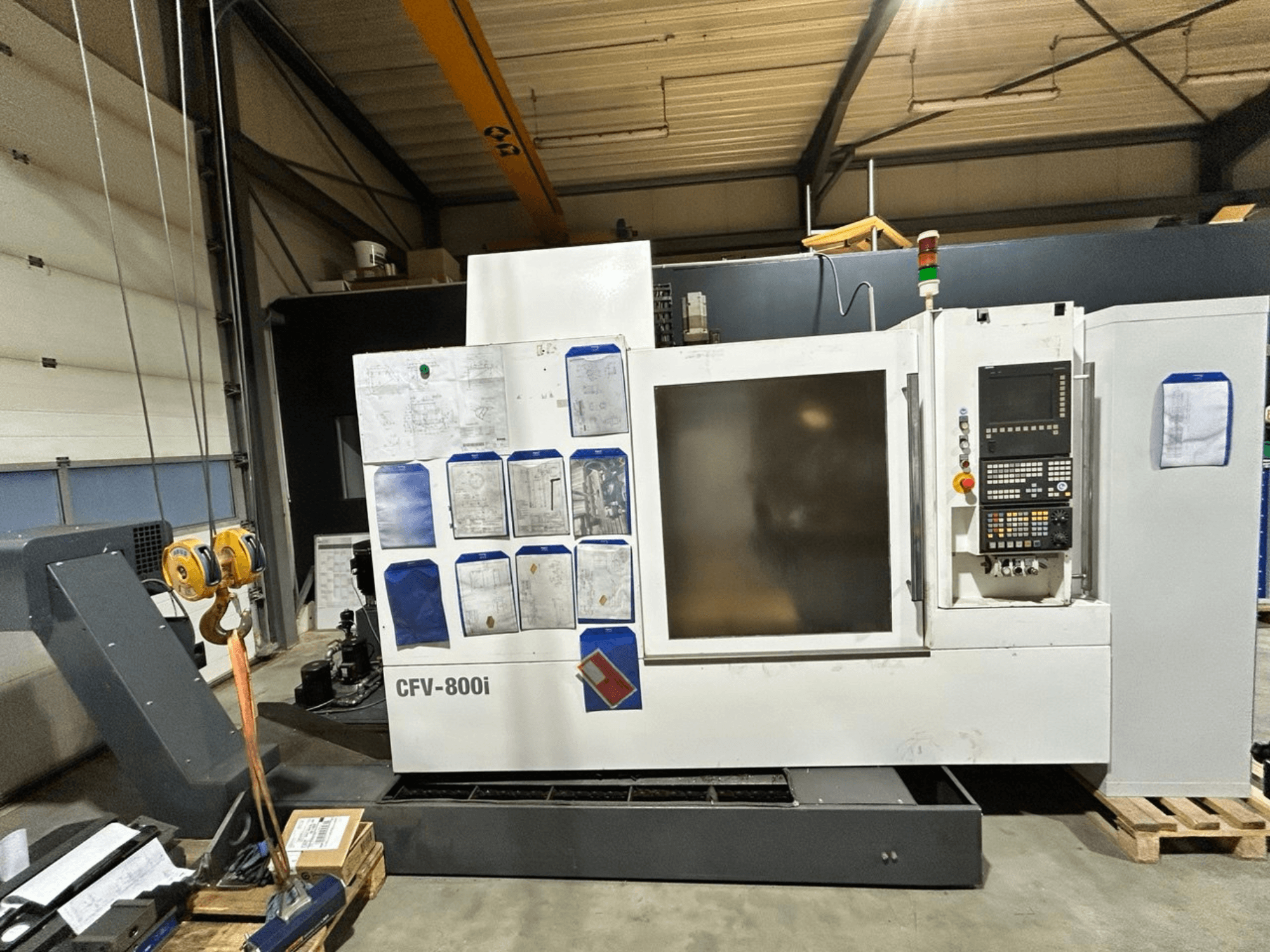 Machine CNC CFV-800i présentée en vue de face, avec panneau de commande, documents sur le côté et pont roulant en configuration d'usine.