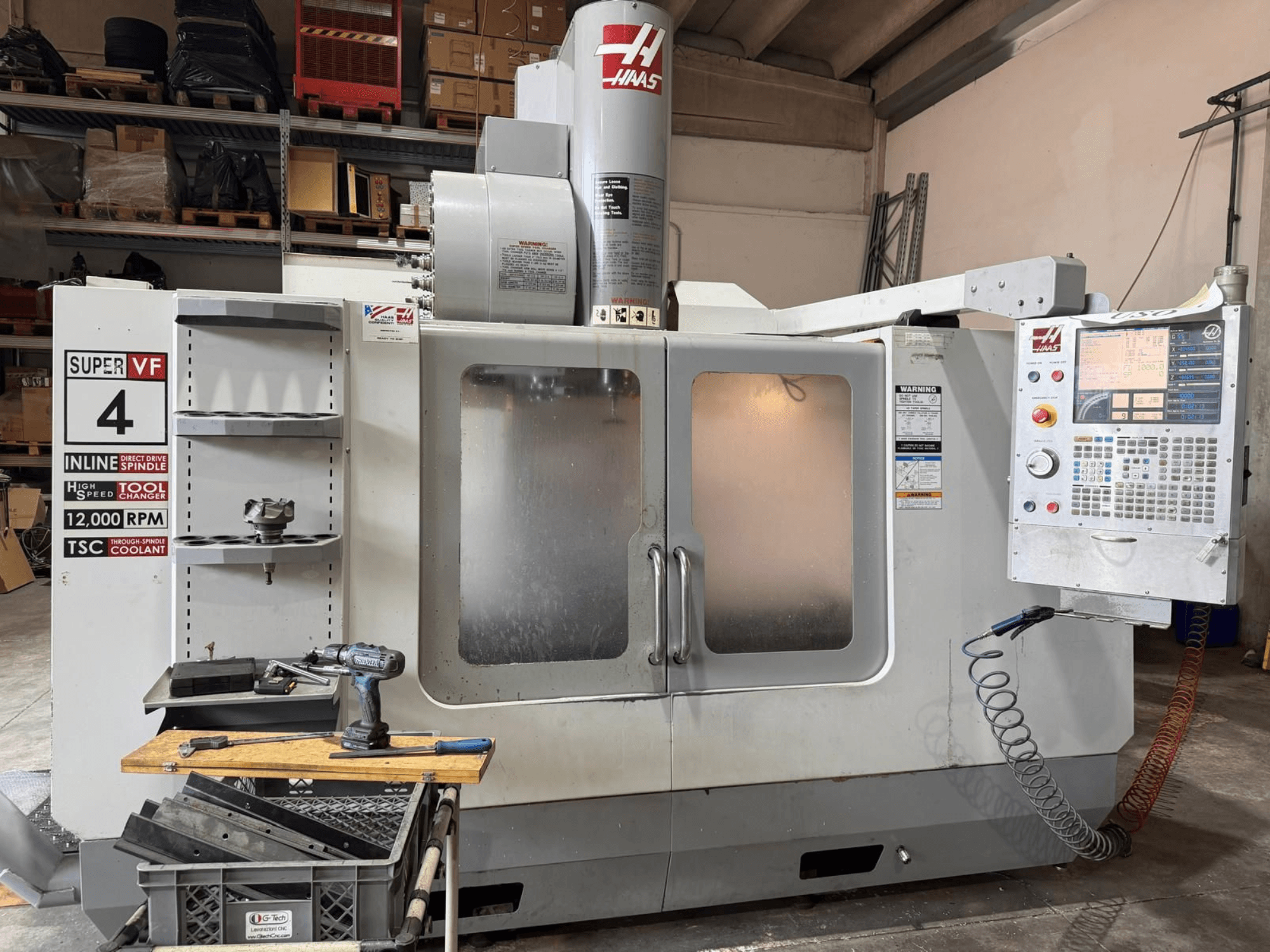 Vue de face du centre d'usinage vertical HAAS VF-4SSHE avec ses commandes, son porte-outils et sa broche tournant à 12 000 tr/min ; machine de haute précision et à grande vitesse.