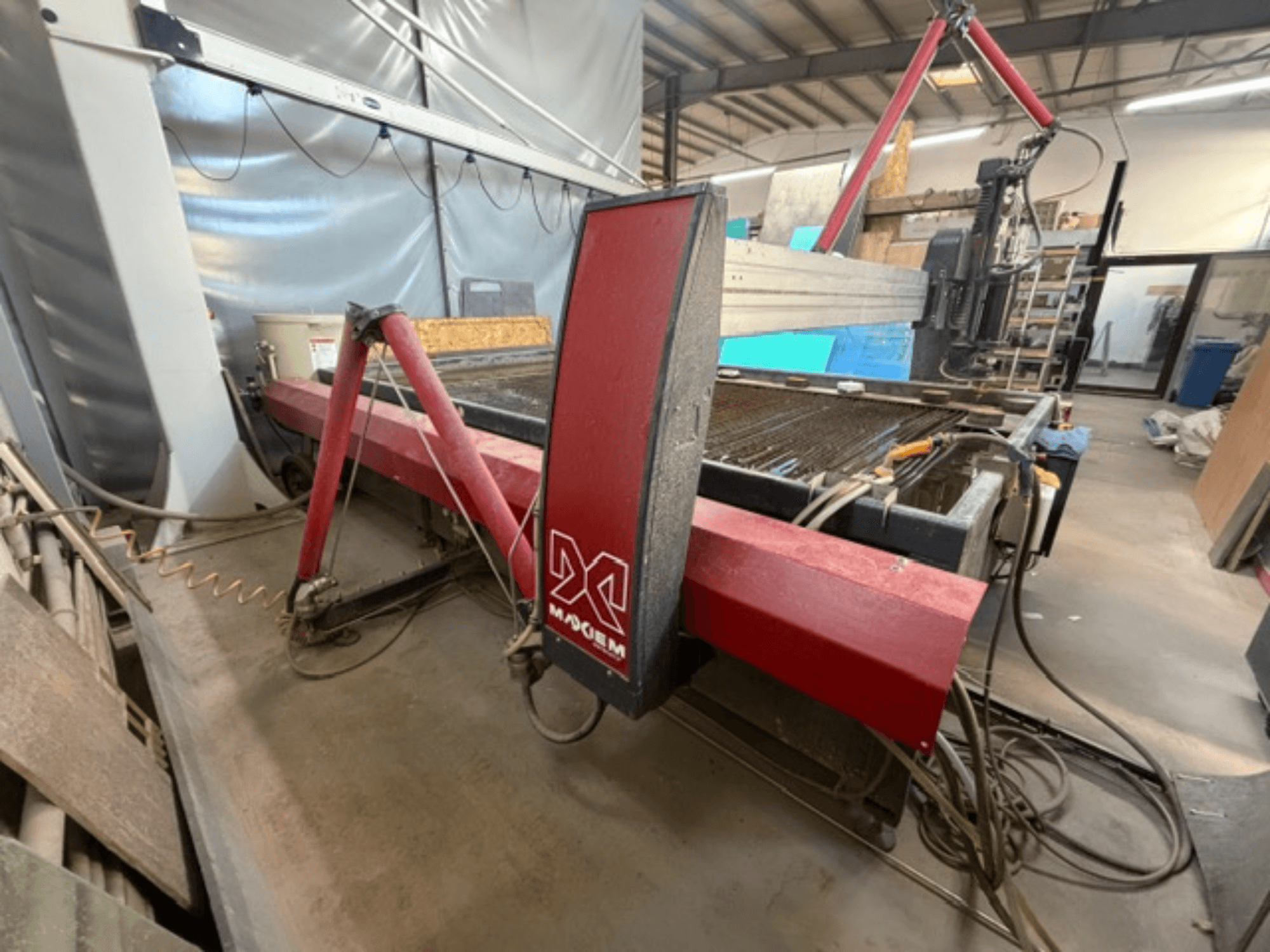 Machine de découpe au jet d'eau rouge de la marque X, vue de côté, montrant les composants mécaniques et les détails de la tuyauterie.