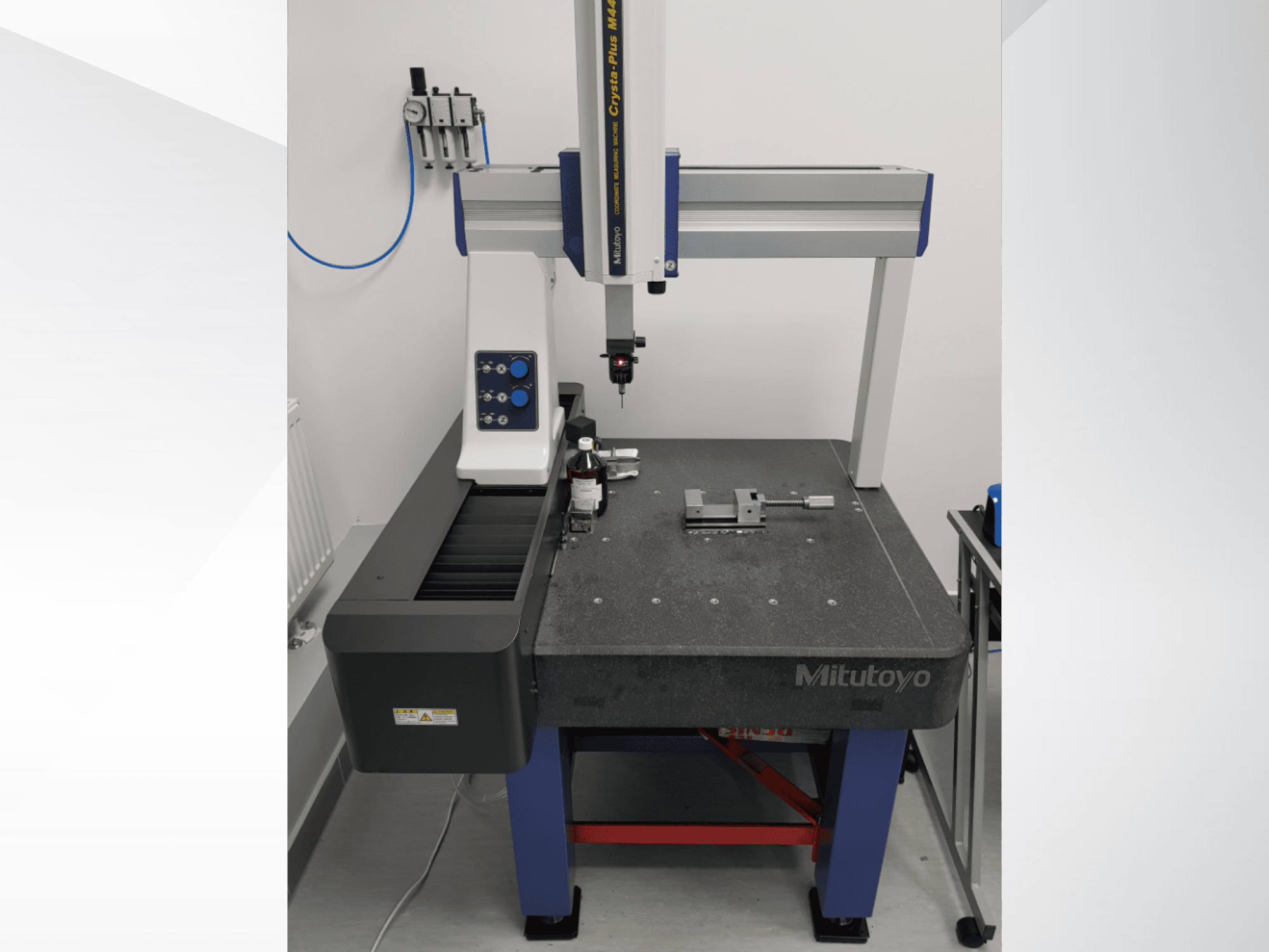 Machine à mesurer tridimensionnelle (MMT) Mitutoyo Crysta-Plus M443 vue de face, avec sonde de mesure, panneau de commande et table d'inspection équipée de fixations.