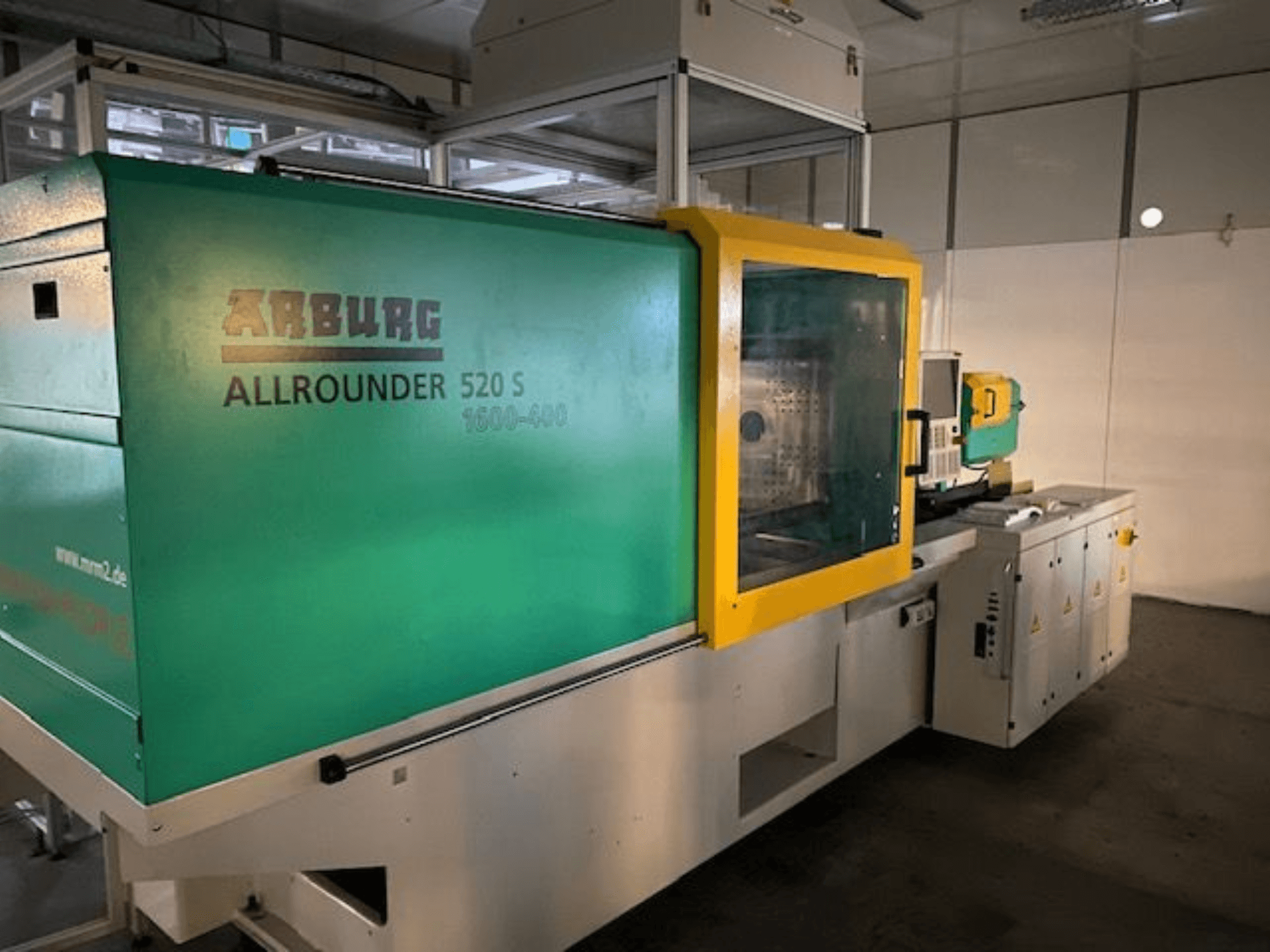Machine de moulage par injection Arburg Allrounder 520 S, vue de côté, avec un extérieur vert et jaune, détails techniques visibles.