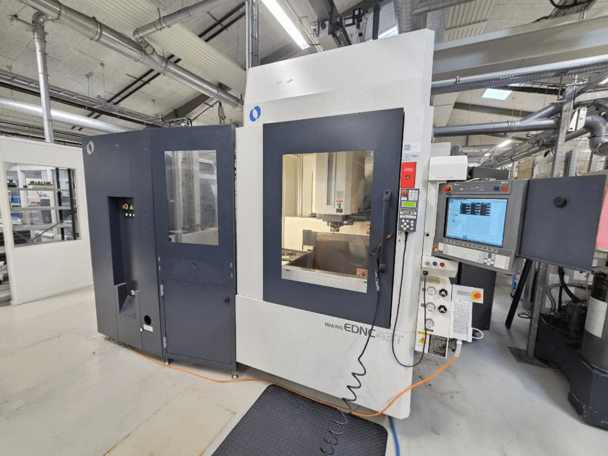 Vue de face d'une machine d'électroérosion par enfonçage Makino EDNC 43T, avec le robot Erowa, les commandes et l'espace de travail visible.
