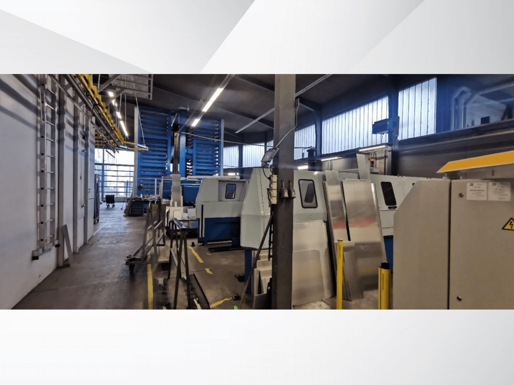 Scène d'atelier industriel présentant plusieurs machines et équipements en vue latérale, avec des surfaces métalliques et des dispositifs de sécurité visibles.