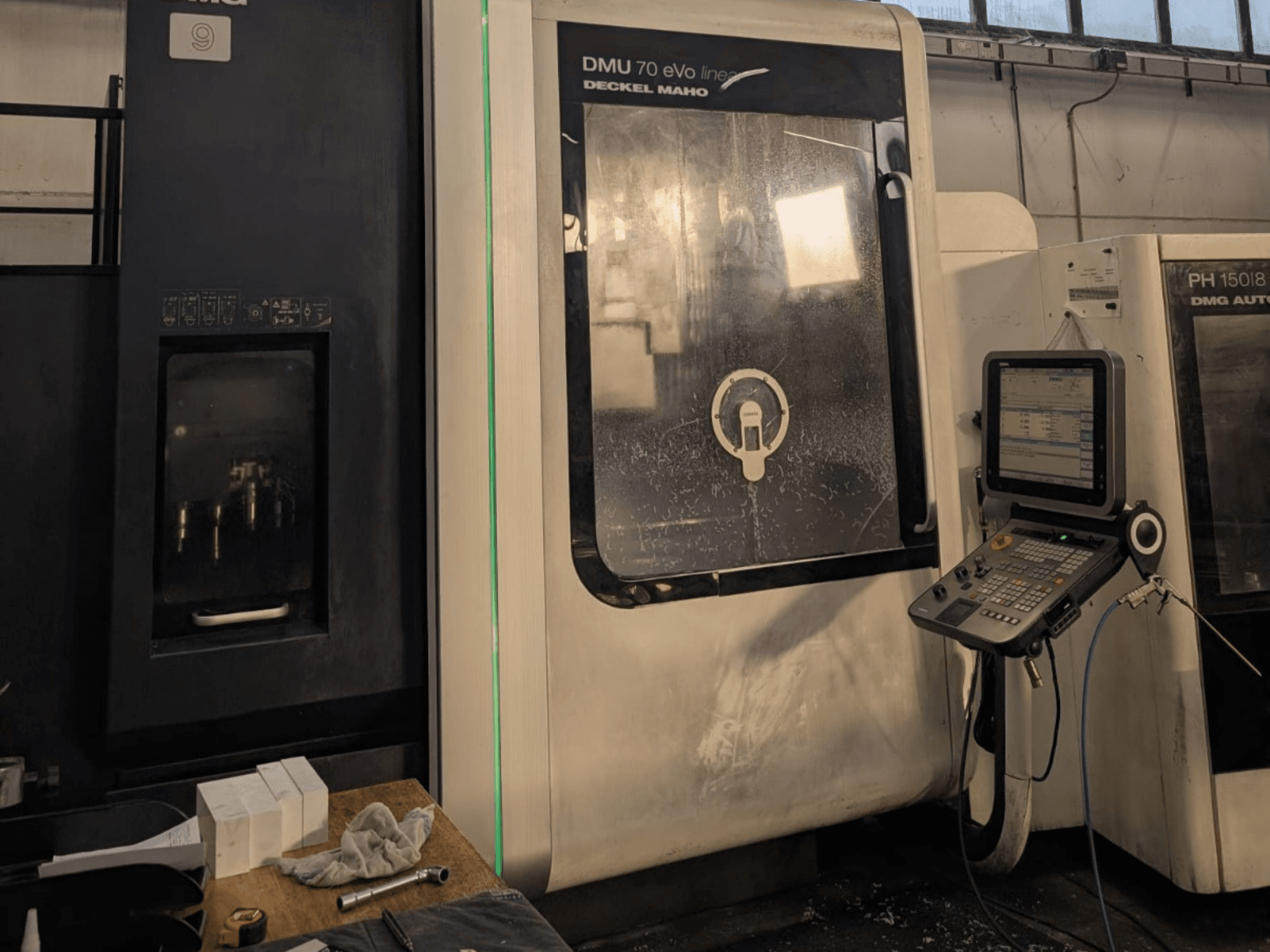 DMG DECKEL MAHO DMU 70 EVO Centre d'usinage vertical linéaire, vue de face avec panneau de commande, outils et espace de travail visibles.