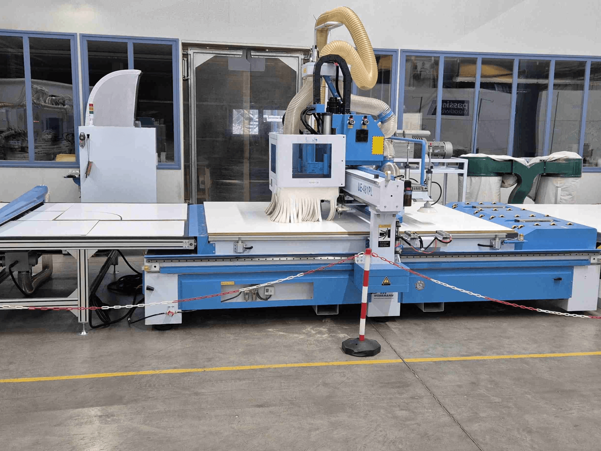 La défonceuse CNC UE-621PL bleue vue de face, avec une grande table de découpe et un système d'extraction de la poussière.