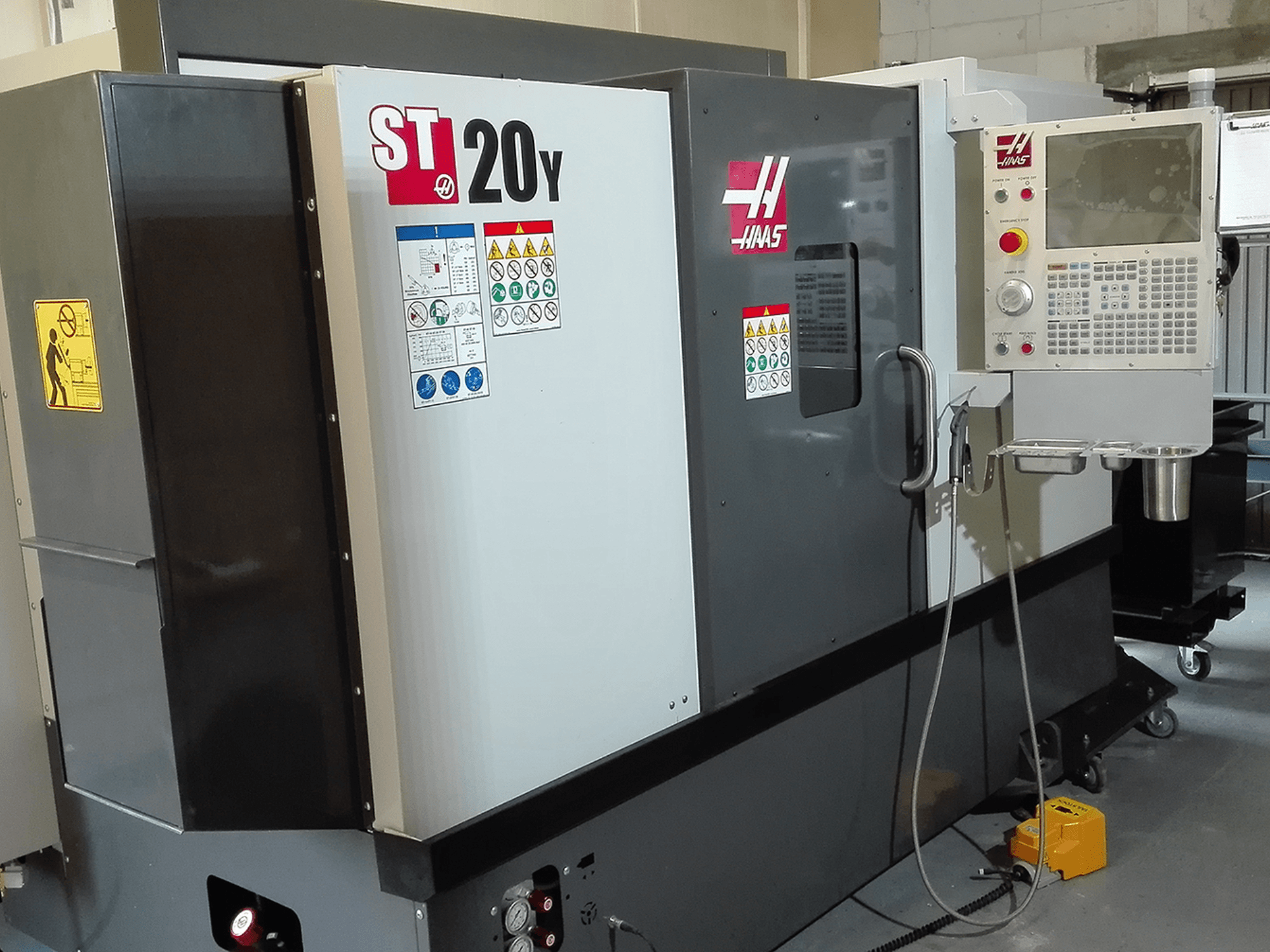 Tour CNC Haas ST20Y vu de face, avec le panneau de commande, les étiquettes de sécurité et le système d'arrosage.