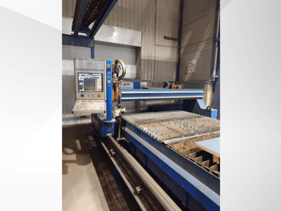 Machine de découpe CNC de PlasmaCam, vue de face montrant le panneau de commande et le banc de découpe métallique à lattes.
