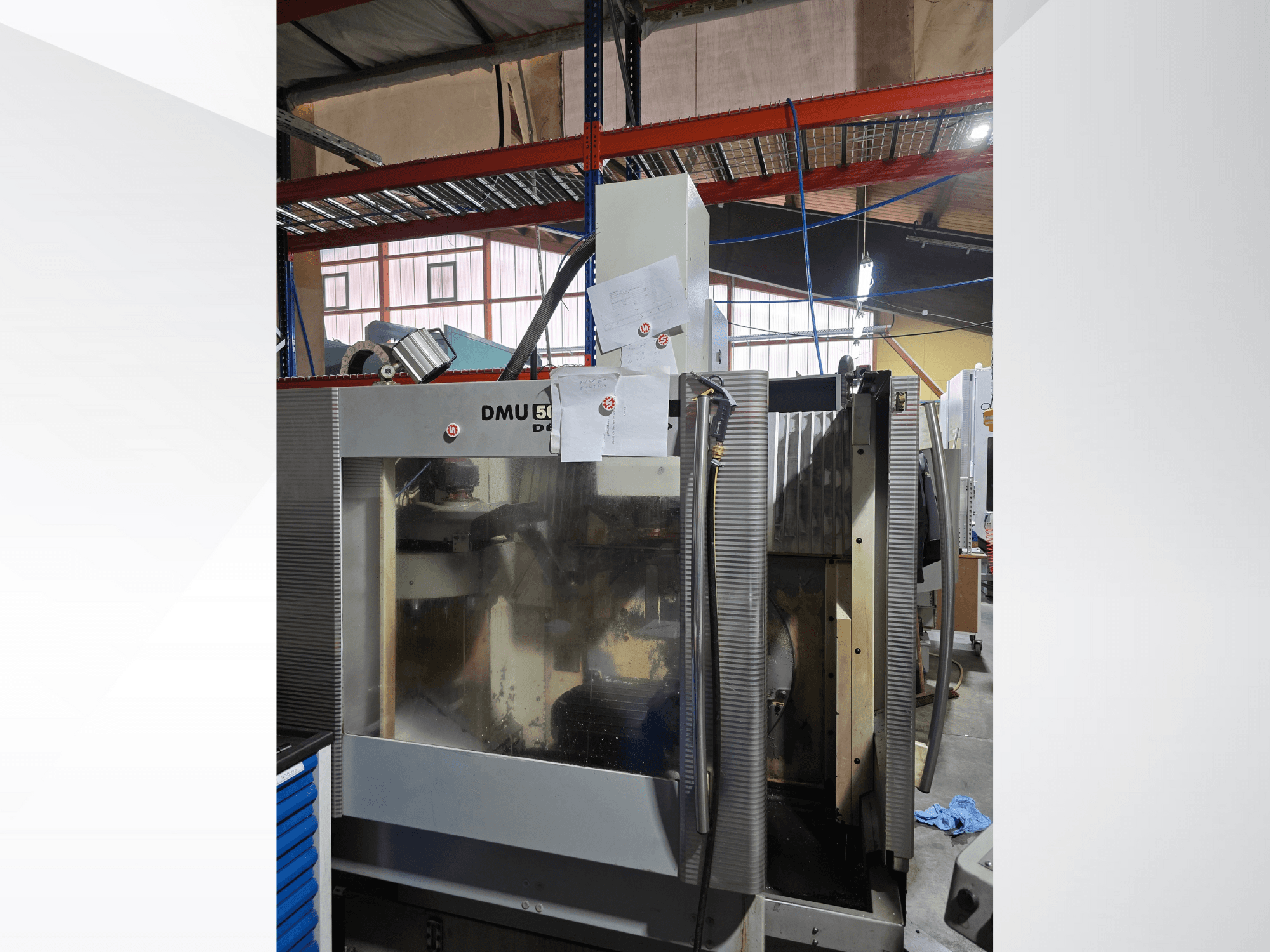 Centre d'usinage CNC à 3 axes DMU 50 dans un atelier, présenté de face, montrant les composants opérationnels et les documents joints.