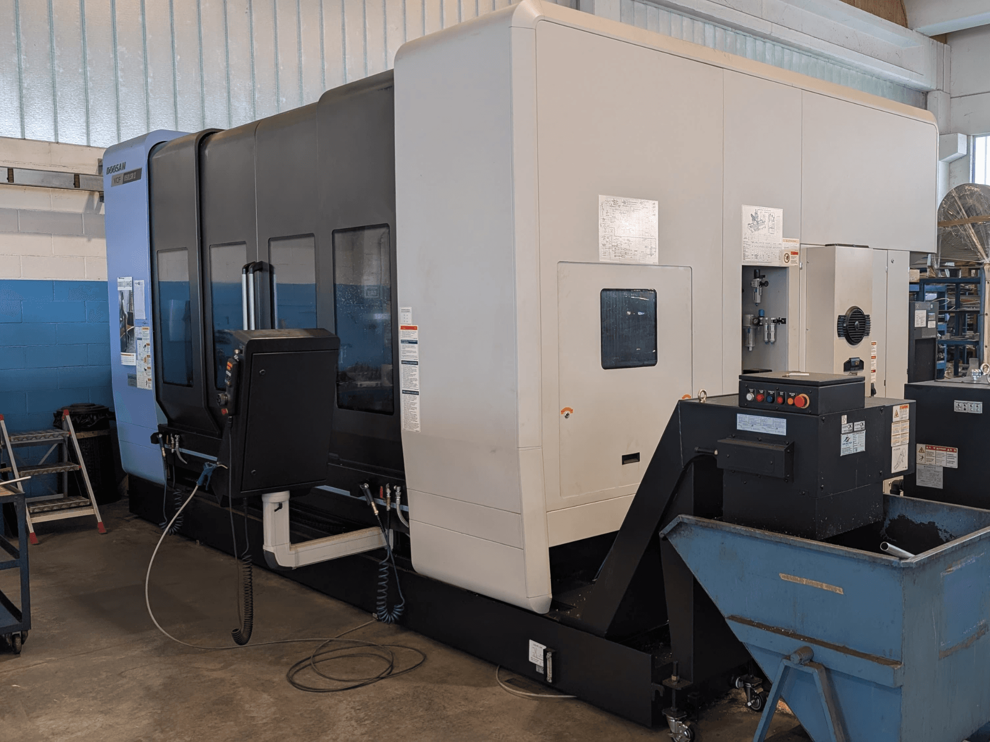 Centre d'usinage vertical DOOSAN VCF850LSR-II vu de profil, mettant en évidence le panneau de commande, le système de refroidissement et sa construction robuste.