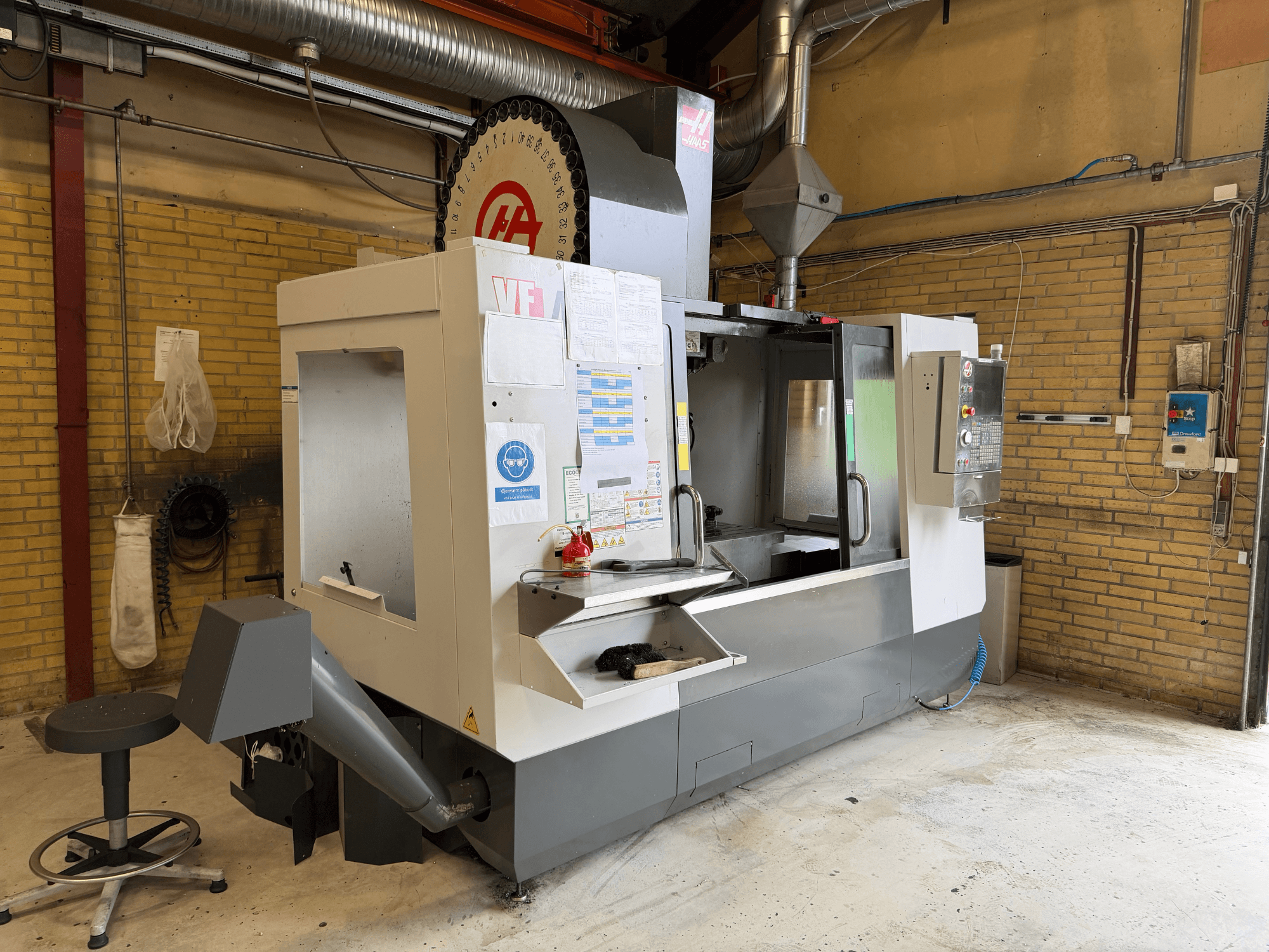 Centre d'usinage vertical HAAS VF-4, vue de face ; on distingue le panneau de commande, le porte-outil et la configuration de production à l'arrière-plan.