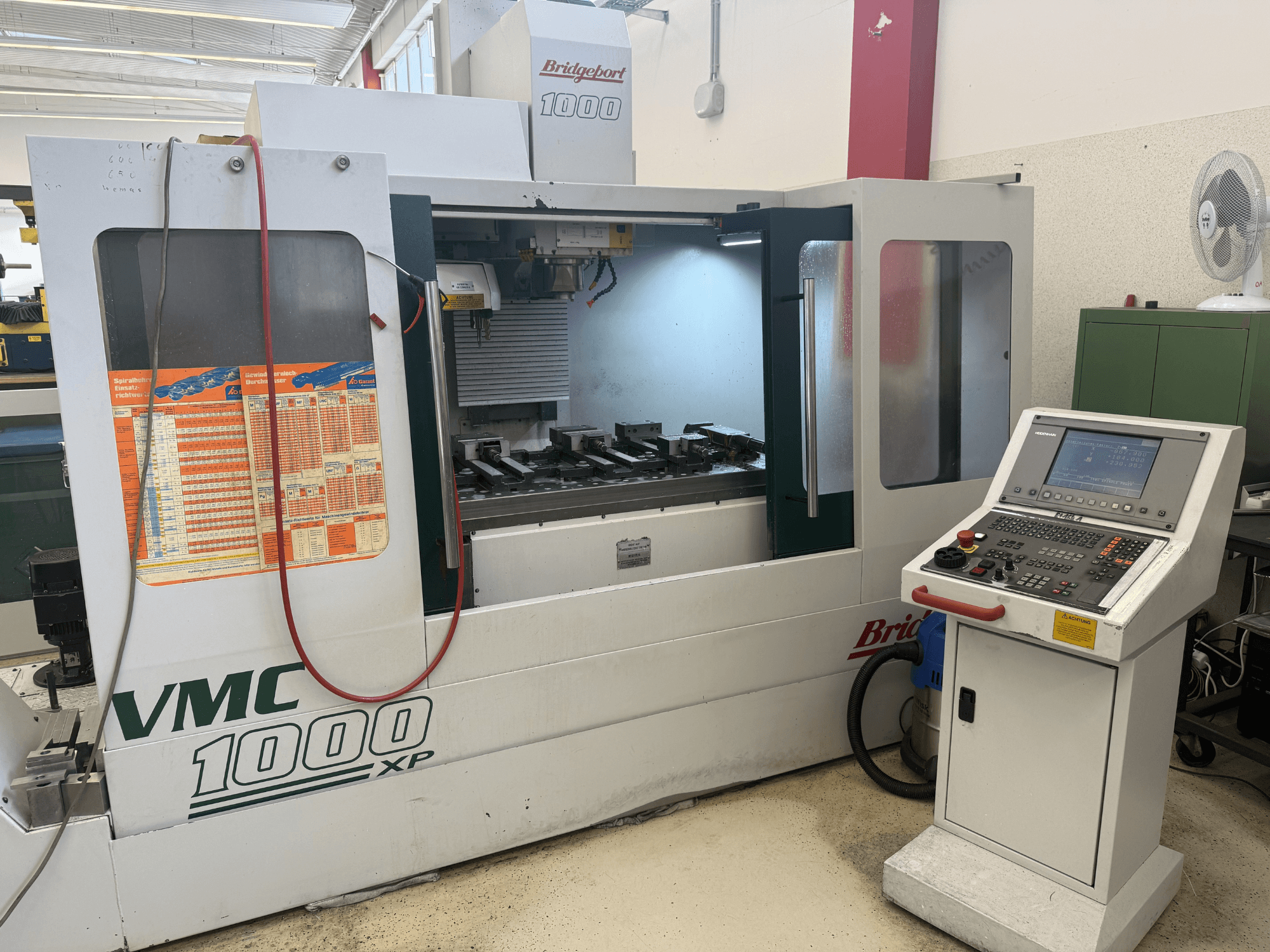 Vue de face du centre d'usinage vertical Bridgeport VMC 1000 XP, mettant en évidence les commandes, la zone de travail et les porte-outils.