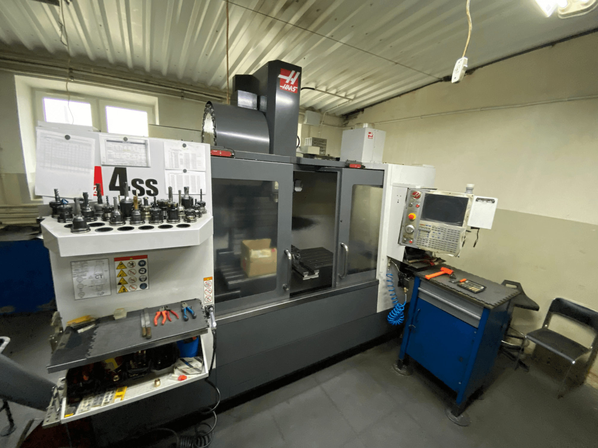 Centre d'usinage vertical Haas VF-4SS, vue de face avec porte-outils et panneau de commande. Les outils et l'espace de travail sont visibles.