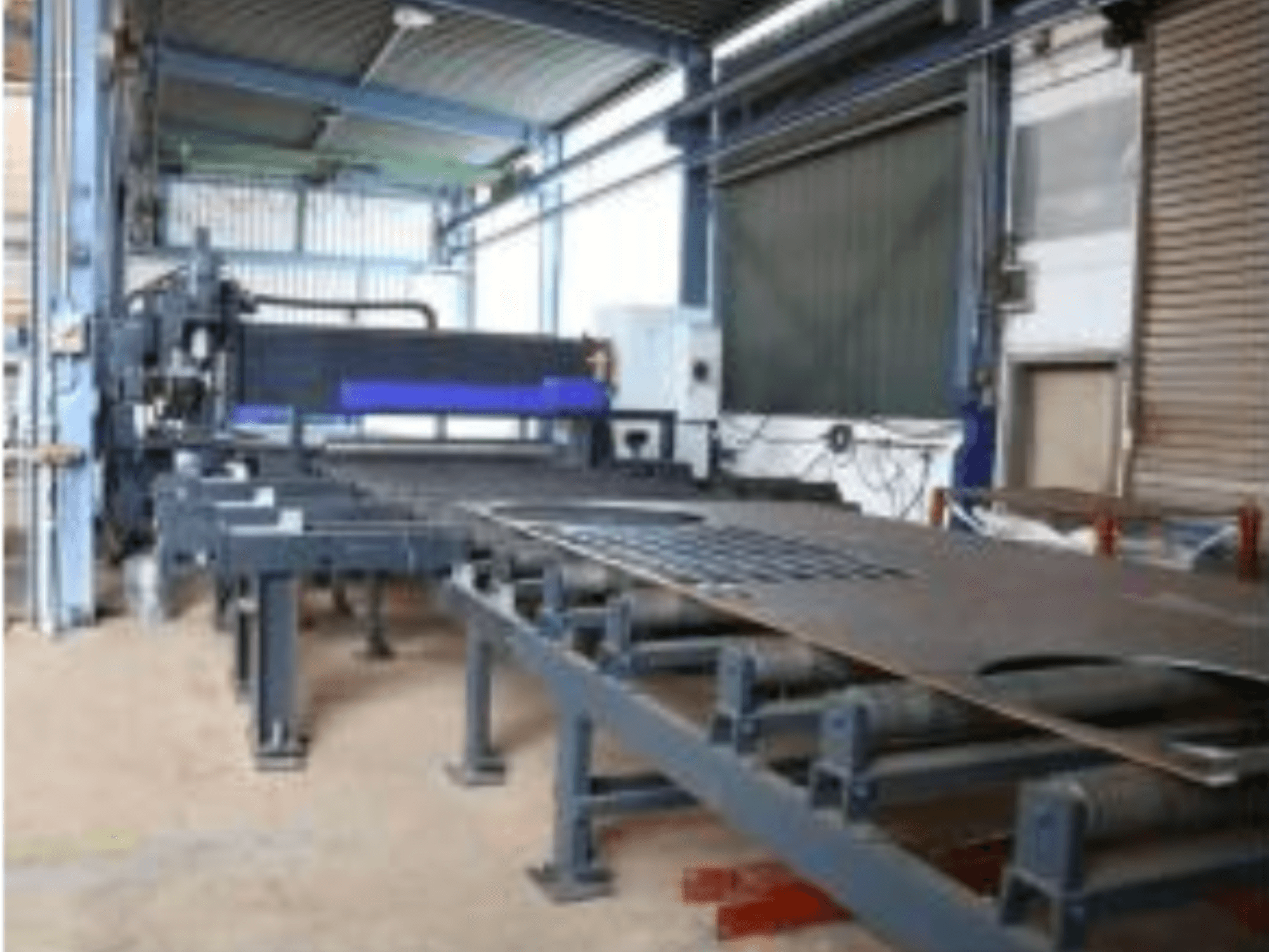 Machine pour la tôlerie Behringer MAG EVO 420 dans un atelier, vue de profil montrant le convoyeur et la zone de découpe.