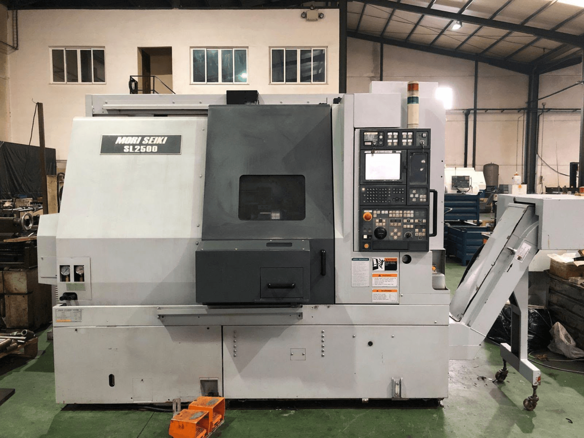Centre de tournage-fraisage DMG Mori Seiki SL 2500 Y, vue de profil montrant le panneau de commande et le convoyeur à copeaux.