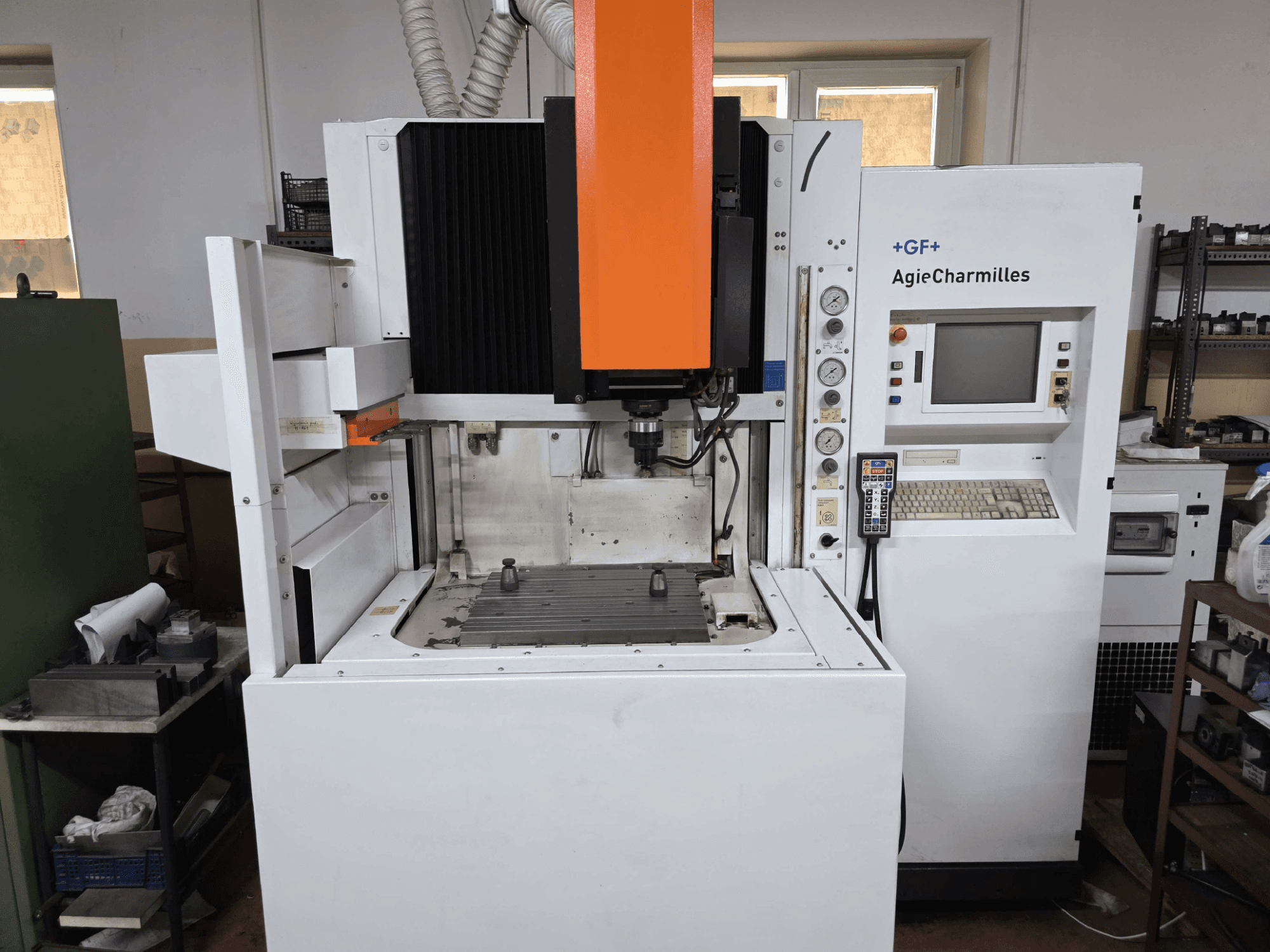 Machine CNC GF AgieCharmilles, vue de face avec une broche orange proéminente, un panneau de commande numérique et une table de perçage montée.