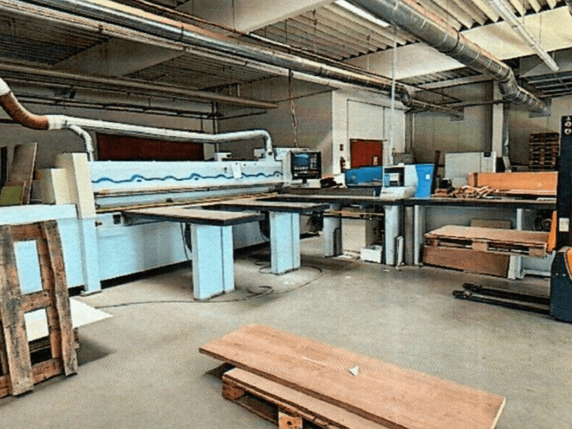 Scie à panneaux HOMAG HPL 11/38/22 dans un atelier, avec une grande table de coupe et une console de présentation, vue de face.