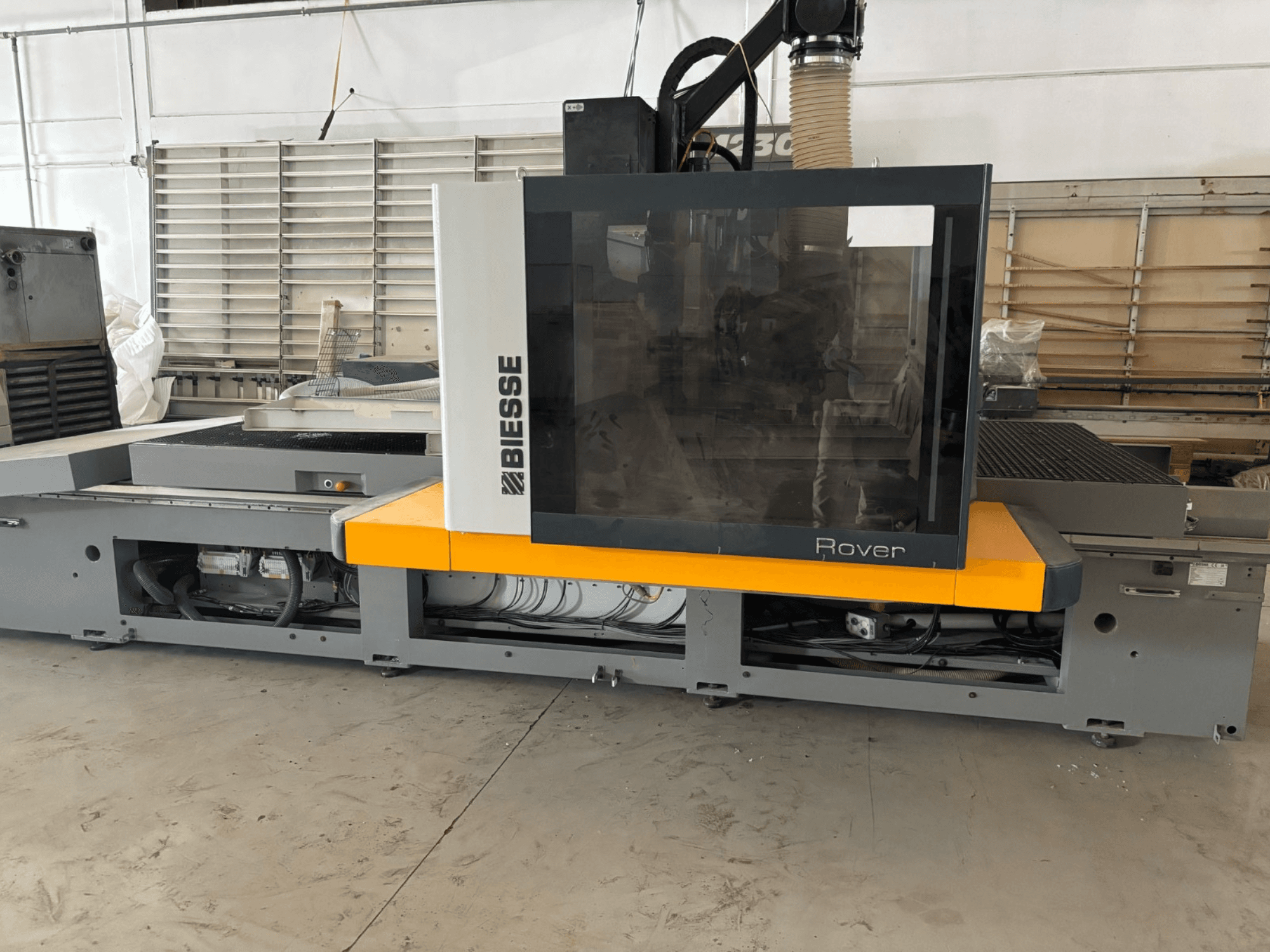 Le centre d'usinage CNC Biesse Rover, vue de face, se caractérise par un grand panneau de commande, des accents jaunes et des composants mécaniques apparents.
