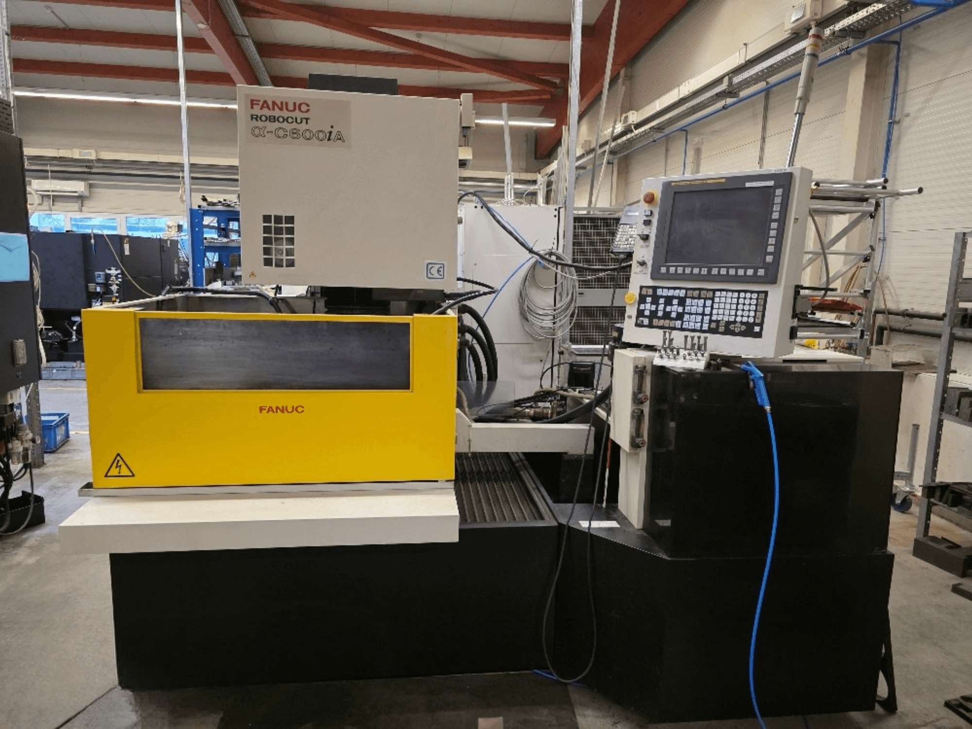 Machine de découpe à fil FANUC Robocut α-C600iA, vue de face, dotée d'un panneau de commande jaune et d'un affichage numérique.