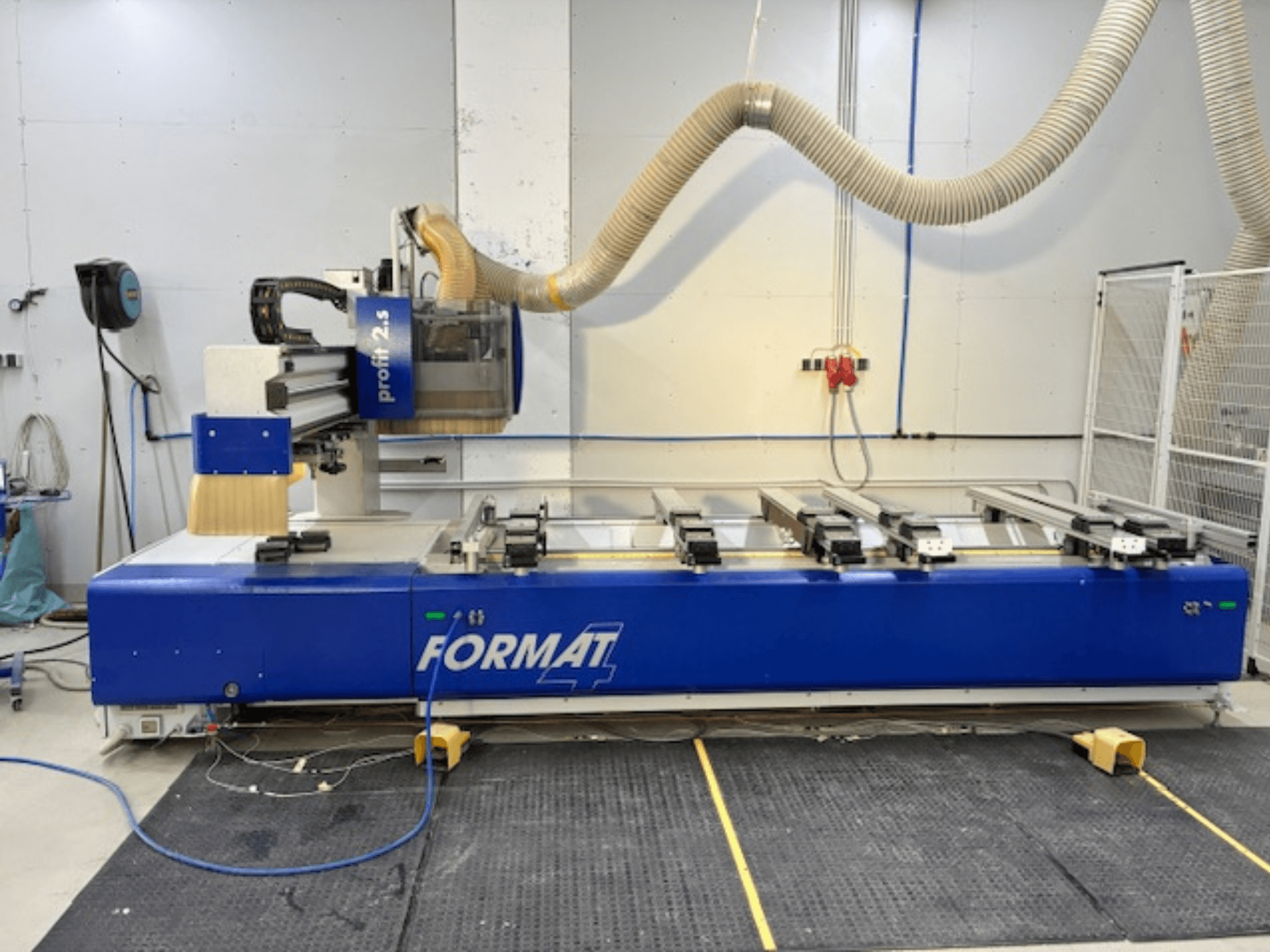 Défonceuse CNC FORMAT 4 bleue, modèle Profit 2.5, vue latérale montrant la zone de coupe et le système d'extraction des poussières, sur un tapis en caoutchouc.