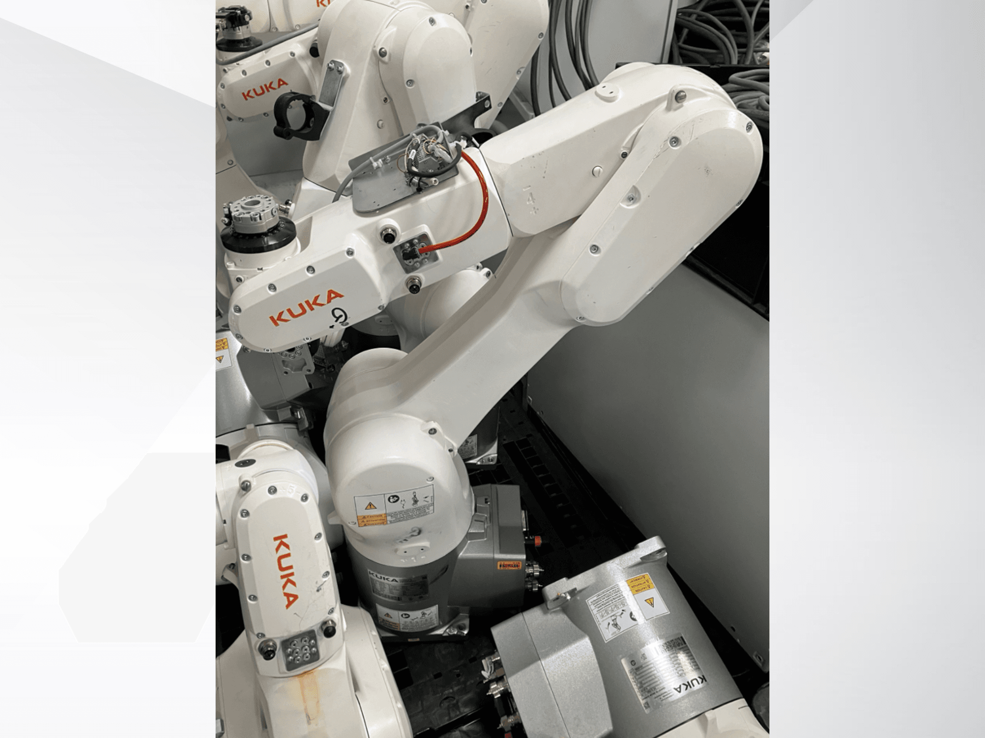 Bras robotique KUKA KR 6 R900 CR, vue latérale ; moteurs et connecteurs visibles, avertissements de sécurité étiquetés et bras mécaniques.