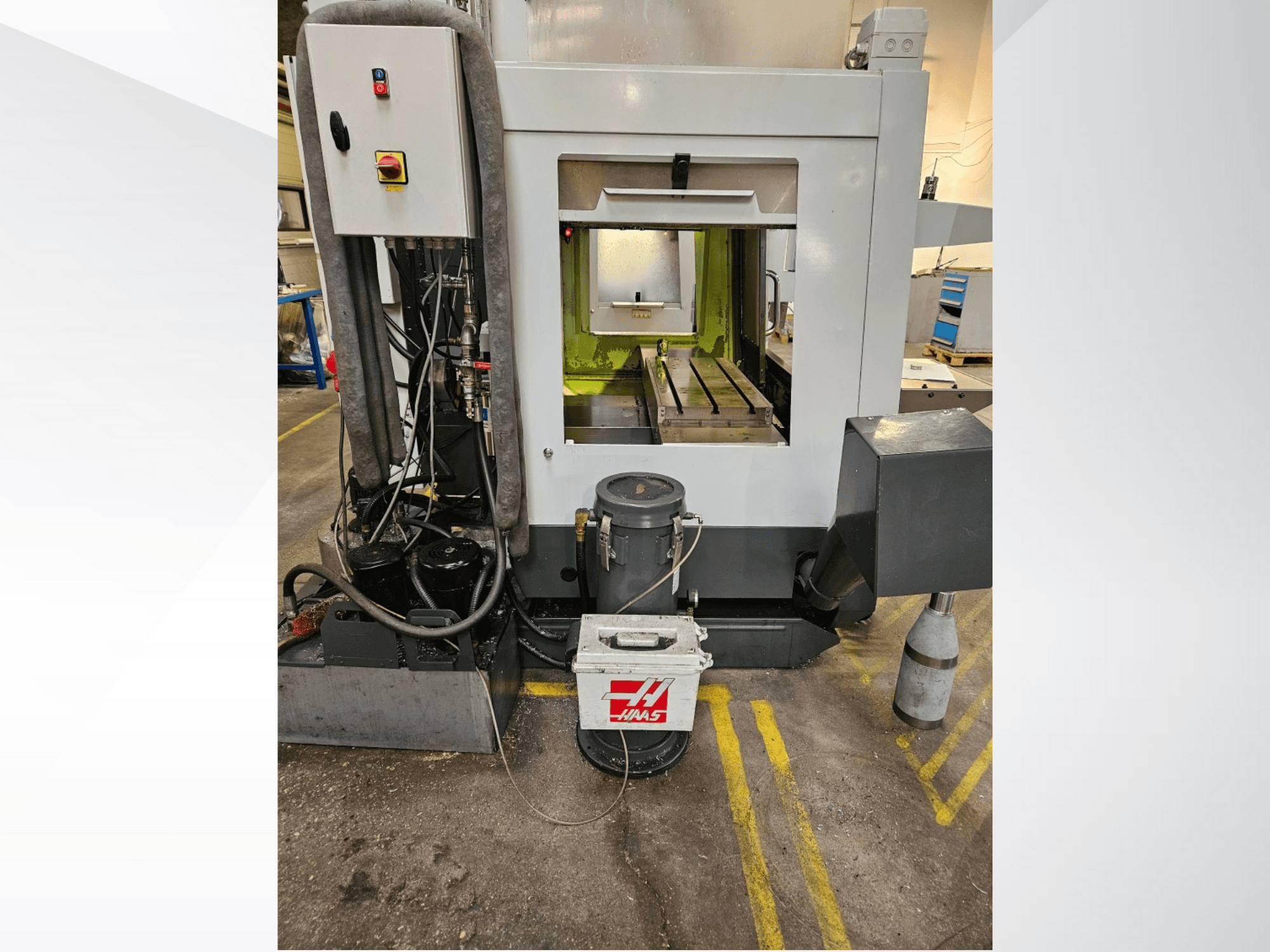 Vue avant de la machine CNC Haas montrant le panneau de commande, le réservoir de liquide de refroidissement et le banc usiné.