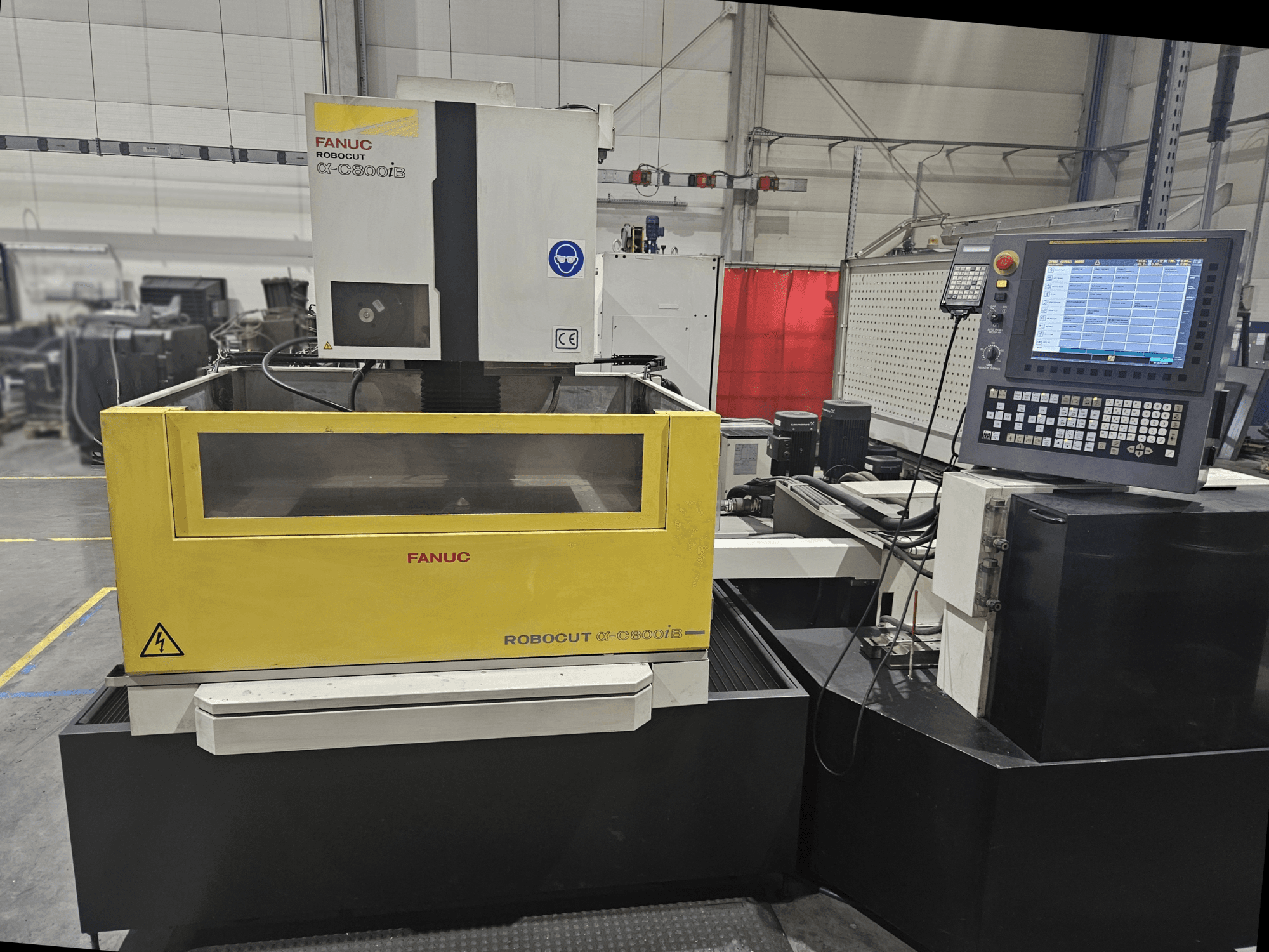 Vue avant de FANUC Robocut α-C600iB avec un corps de machine jaune et gris, un panneau de commande CNC et un affichage opérationnel.