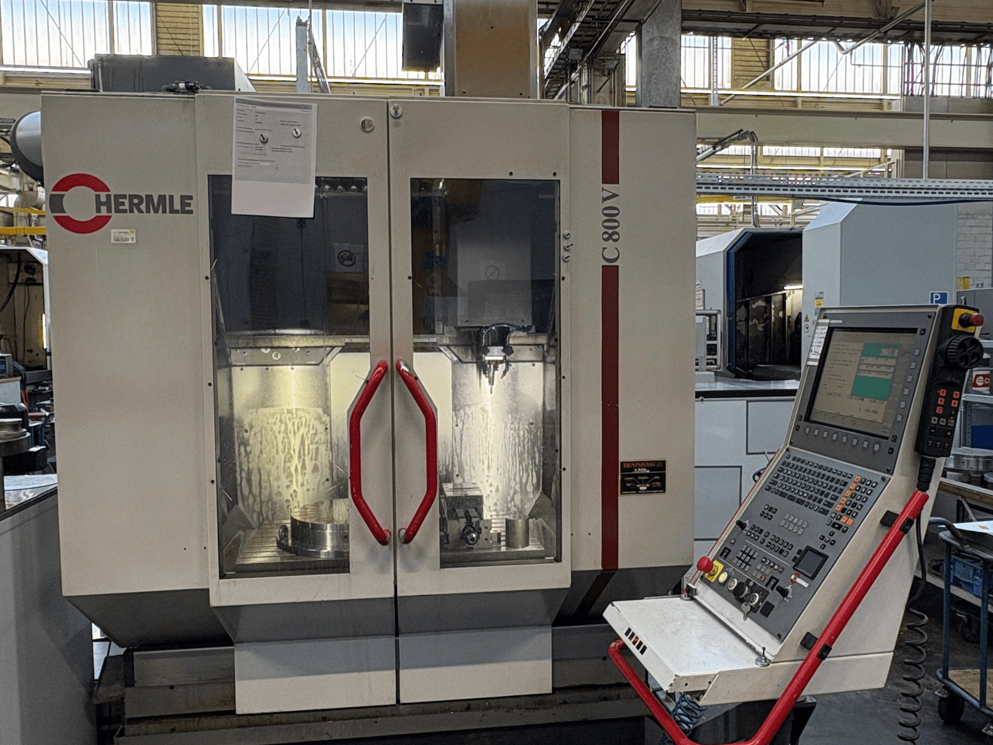 Centre d'usinage vertical HERMLE C 800 V, vue de face, avec des portes à poignées rouges et un panneau de commande à droite.