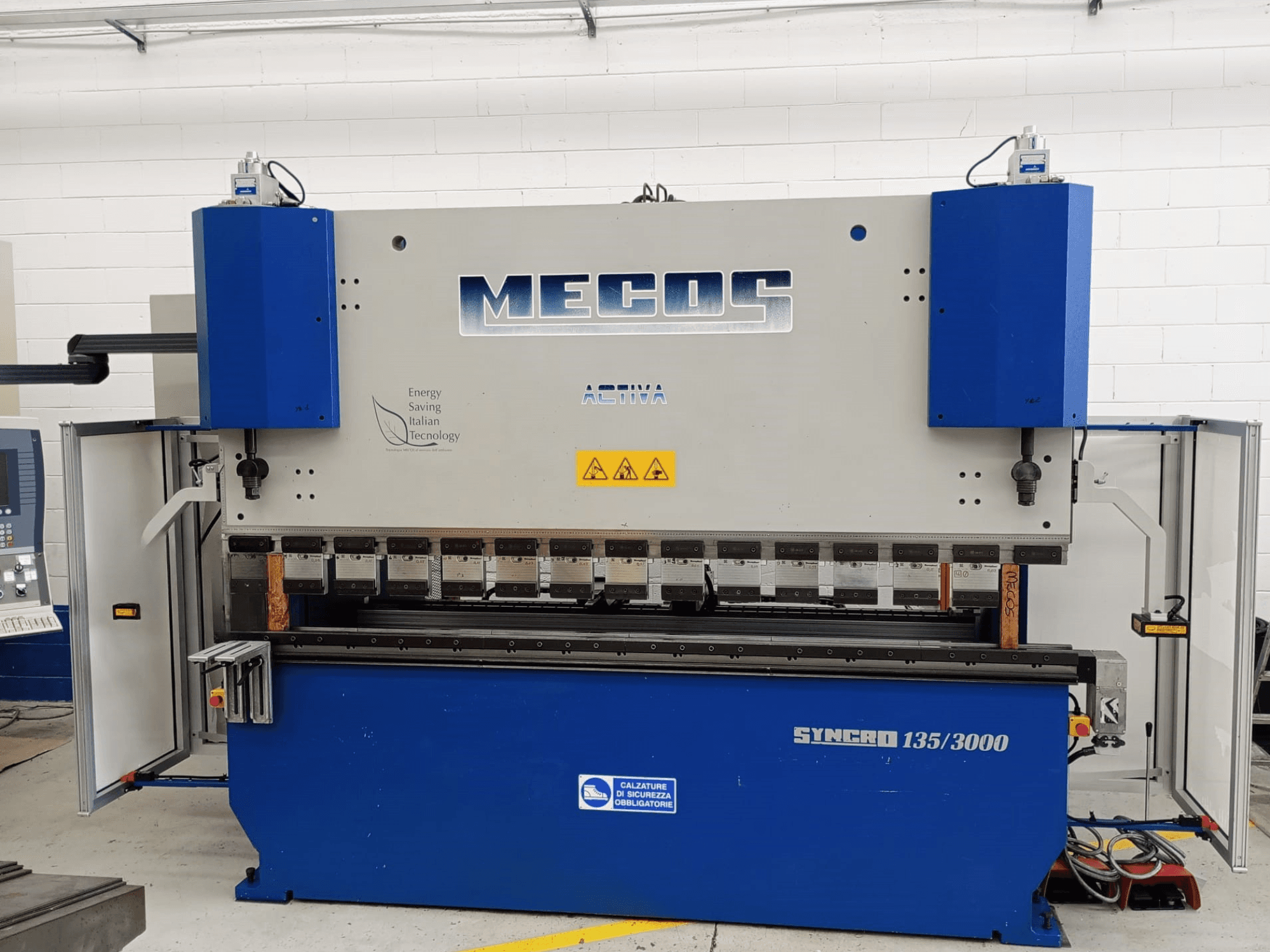 Vue avant de la presse plieuse MECOS SYNCRO 135/3000, présentant les commandes, les outils de pliage et les dispositifs de sécurité.