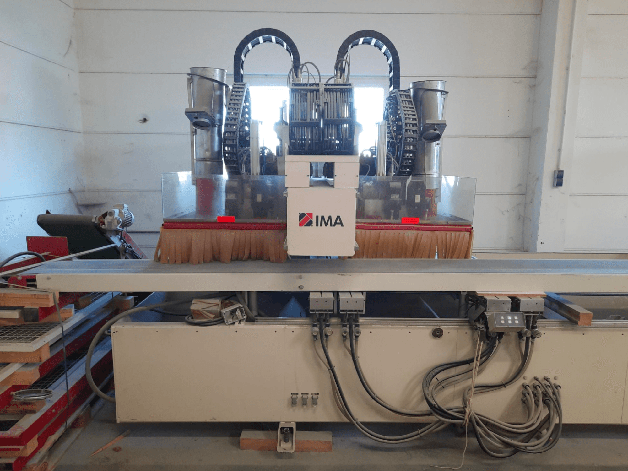 Centre d'usinage CNC pour le bois IMA BIMA 610 V vu de face, avec ses brosses, ses commandes et sa table de travail.
