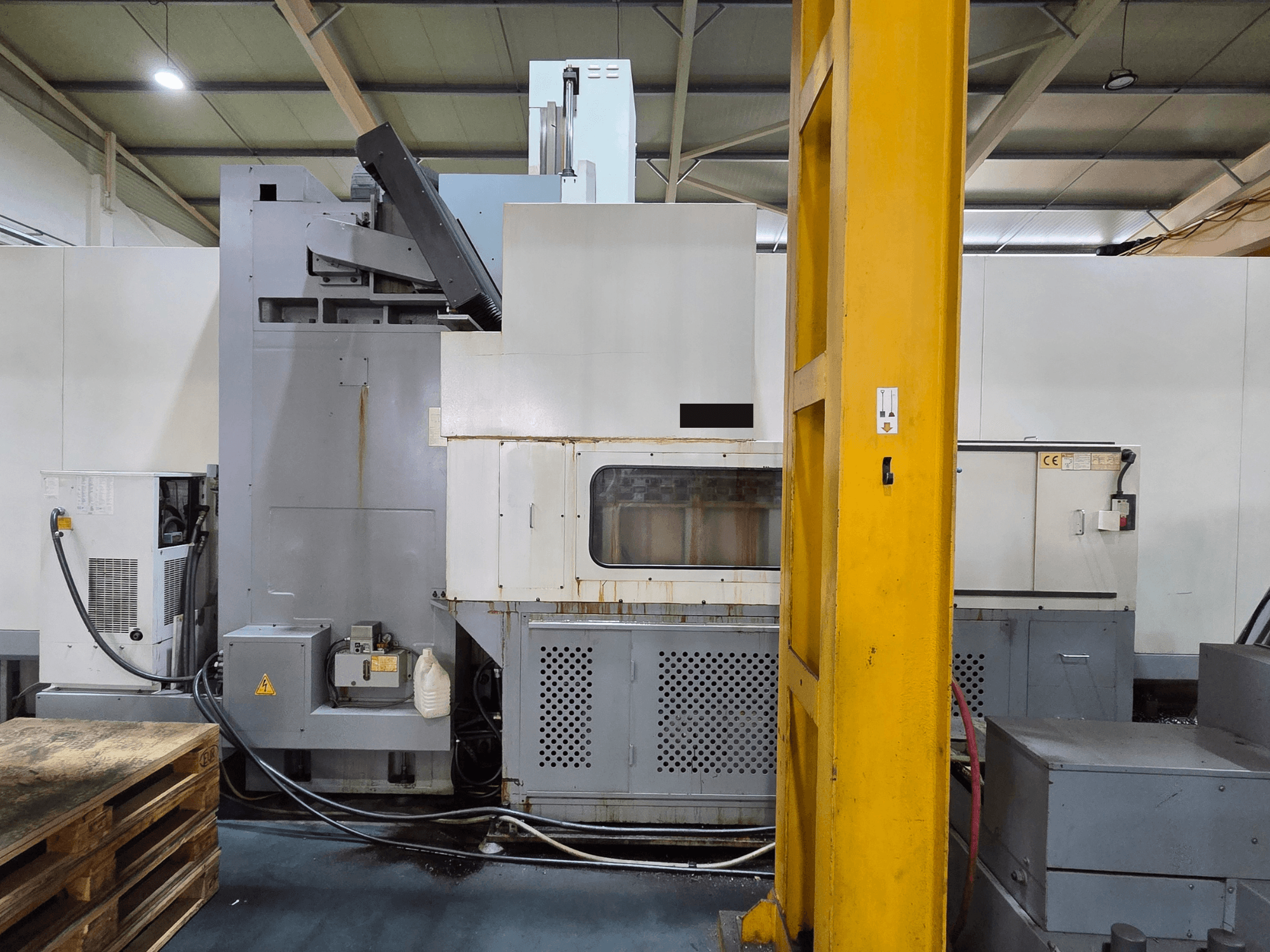 Centre d'usinage vertical HARTFORD HB 3150/S dans un atelier, vue latérale montrant le corps de la machine et les composants attachés.