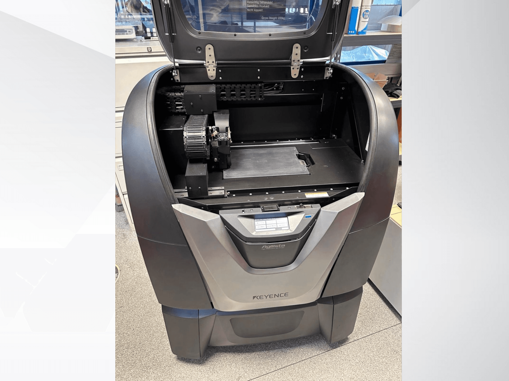 L'imprimante 3D KEYENCE Agilista, vue de face, révèle la partie supérieure ouverte, la grande plateforme de construction et les composants mécaniques internes.