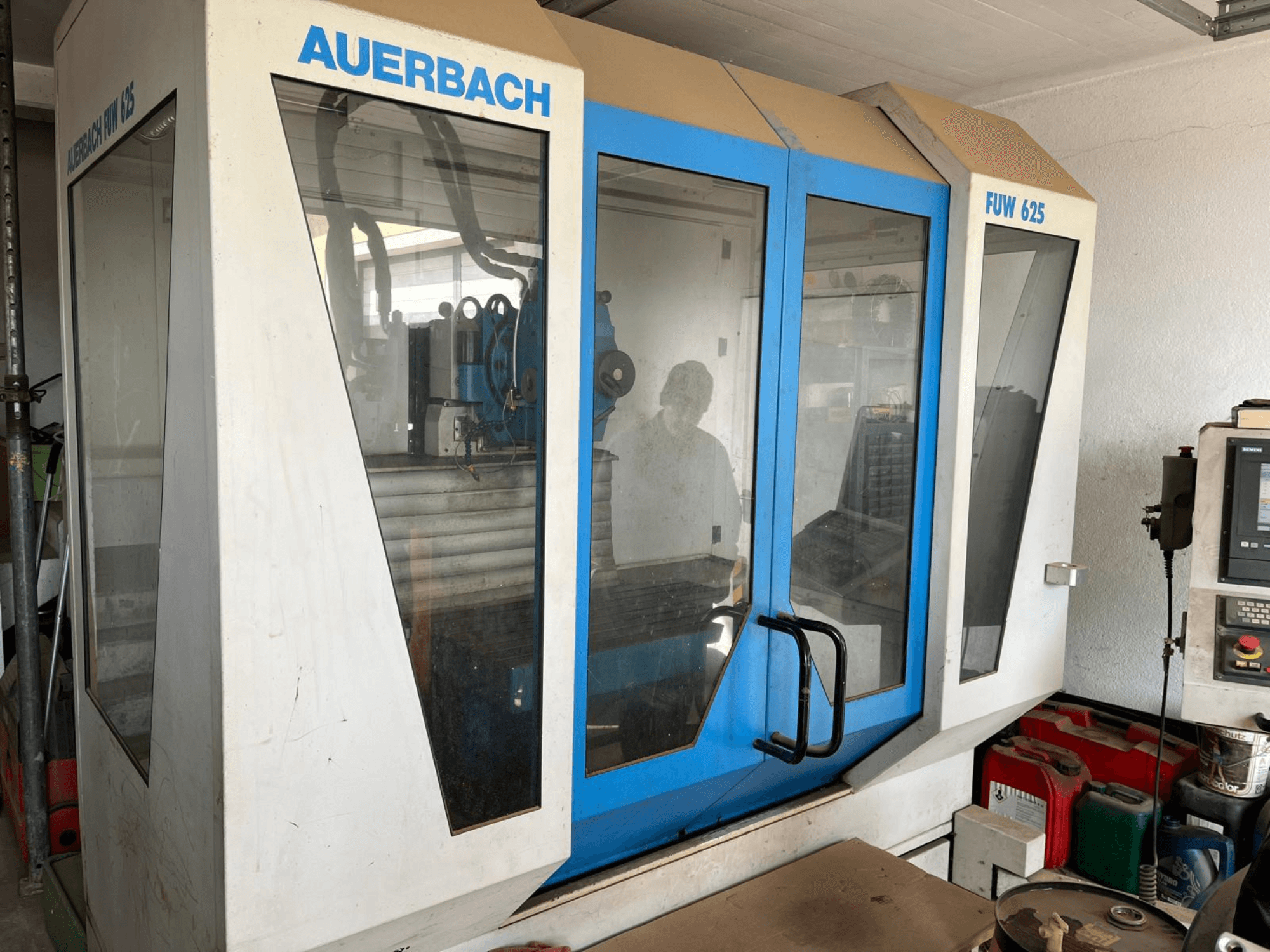 Centre d'usinage universel Auerbach FUW 625 en vue latérale, avec des panneaux en verre et un panneau de commande à droite.