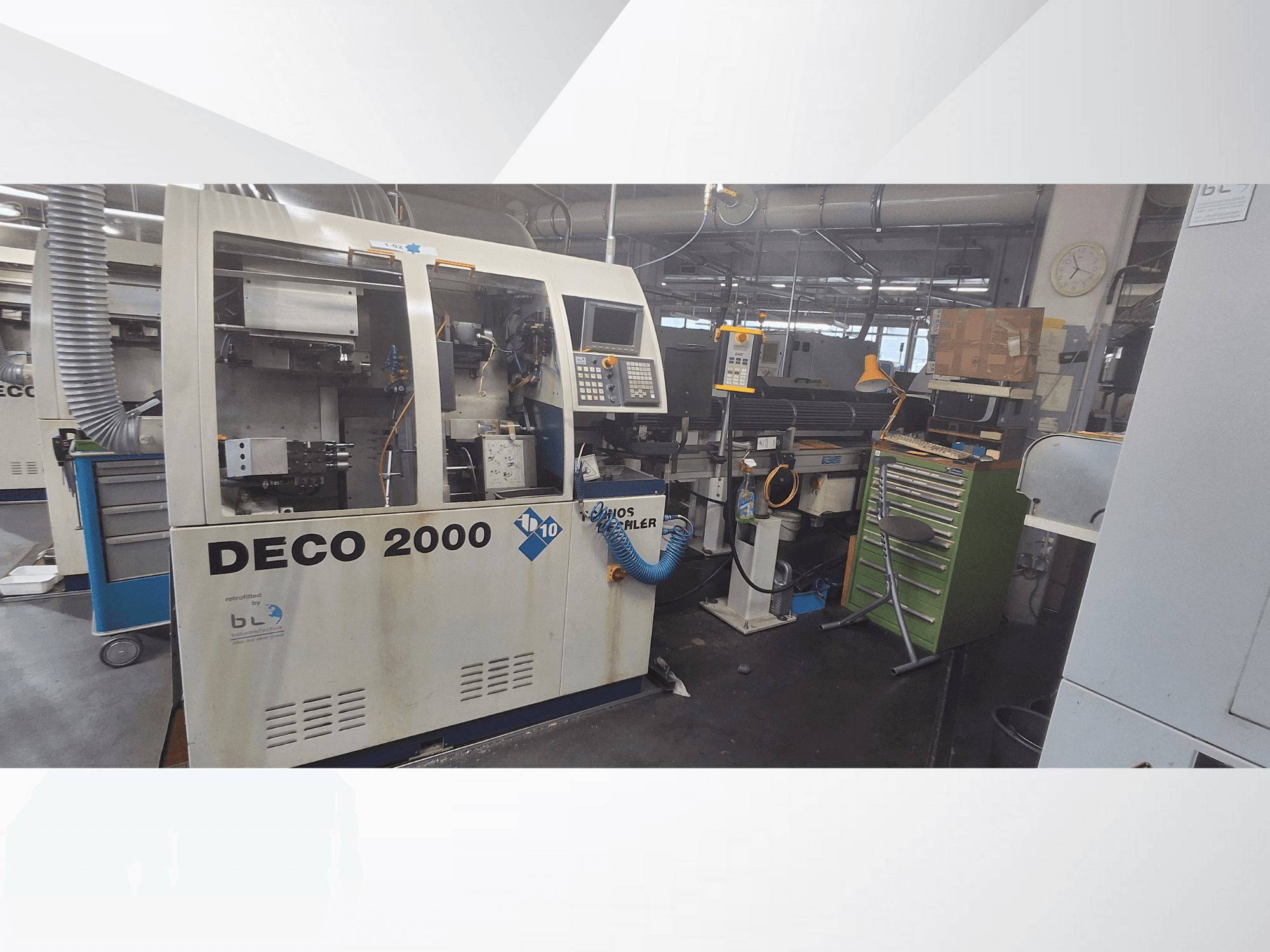 Machine DECO 2000 vue de face, avec panneau de commande, tuyaux et espace de travail encombré d'outils et de boîtes.