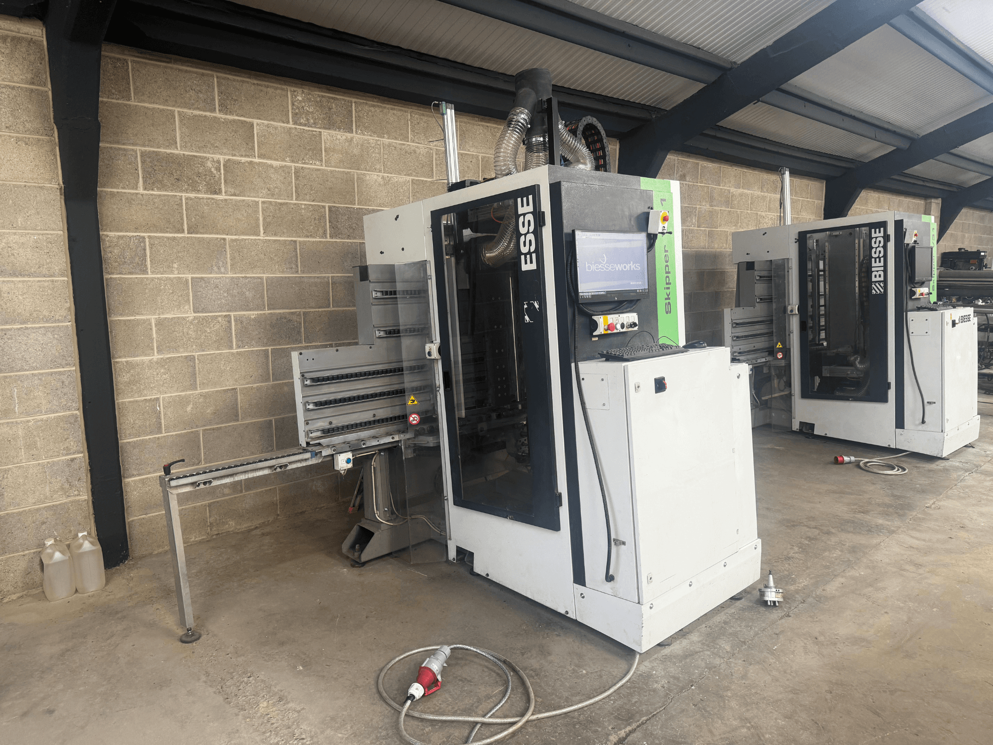 Perceuse à bois BIESSE Skipper v31 en vue latérale, avec panneau de commande et machines adjacentes, dans un atelier.