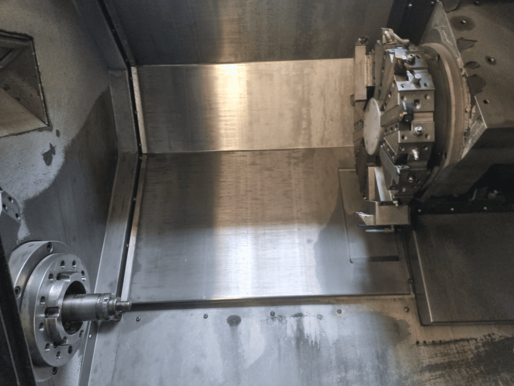 Vue intérieure d'un tour CNC, doté d'une broche rotative et d'une surface de travail en métal, illustrant l'ingénierie de précision industrielle.