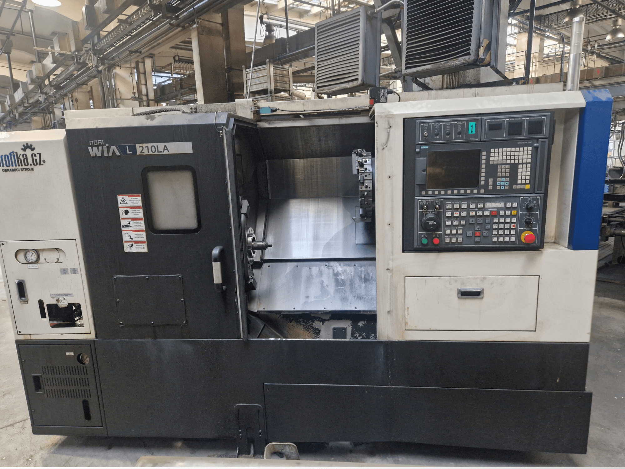 Tour CNC WIA L210LA, vue de face, panneau de commande avec boutons, écran et zone d'usinage visible.