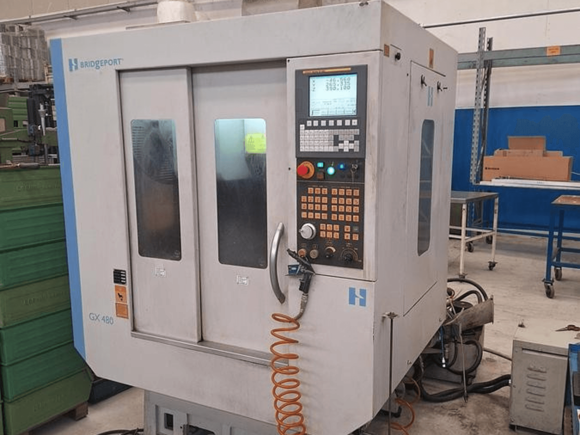 Centre d'usinage vertical Bridgeport GX 480 vu de face, avec un panneau de commande, deux portes vitrées et un tuyau flexible.