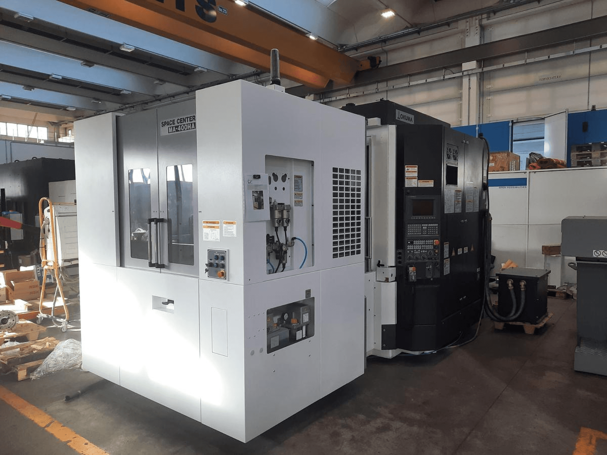 Vue avant des machines CNC SPACE CENTER IM-400HAA et OKUMA, présentant les différentes commandes et les étiquettes des fabricants.