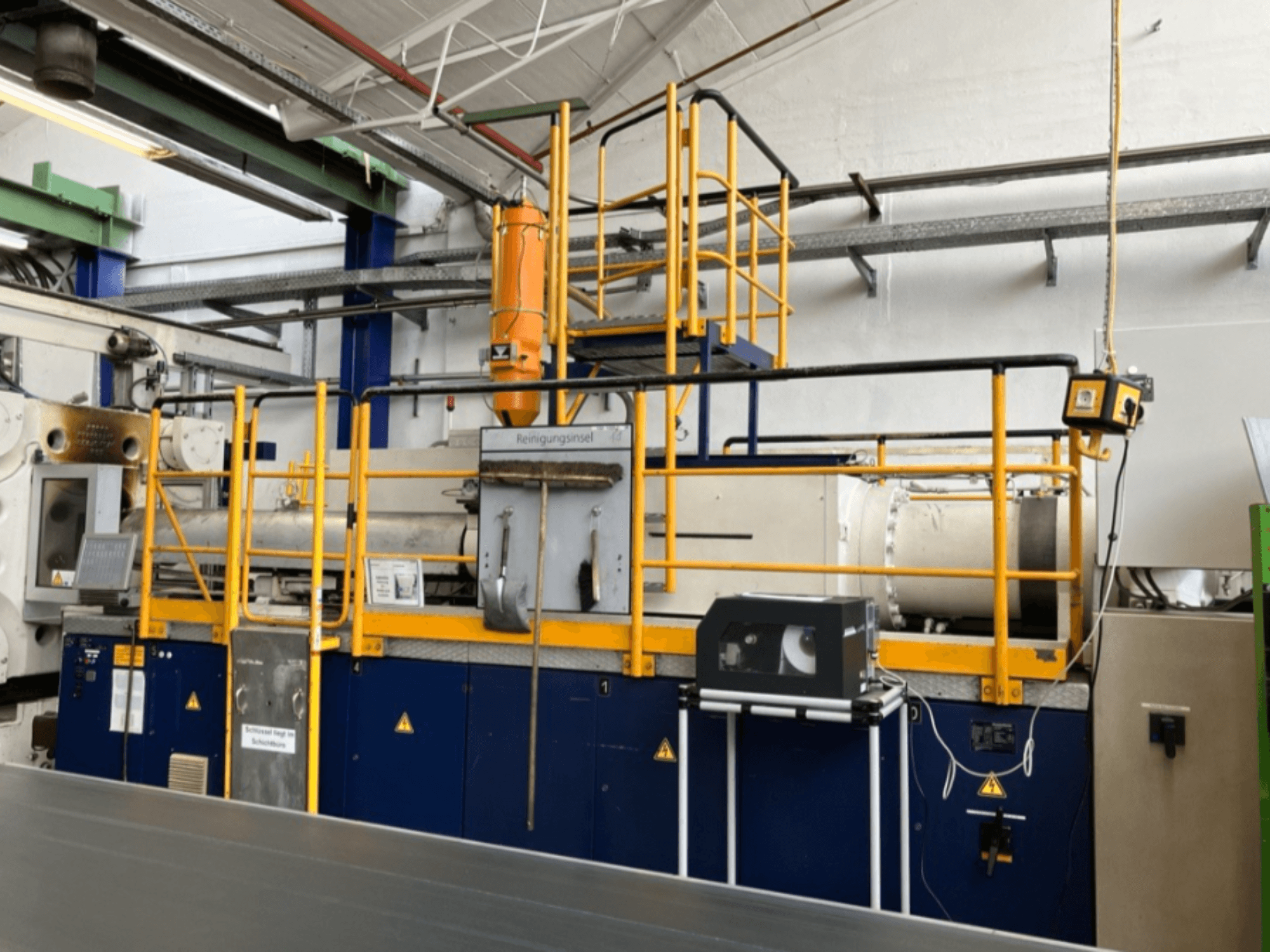 Machine de moulage par injection hydraulique Krauss Maffei 1000-8000 M, vue de côté avec le garde-corps de sécurité et le panneau de commande visibles.