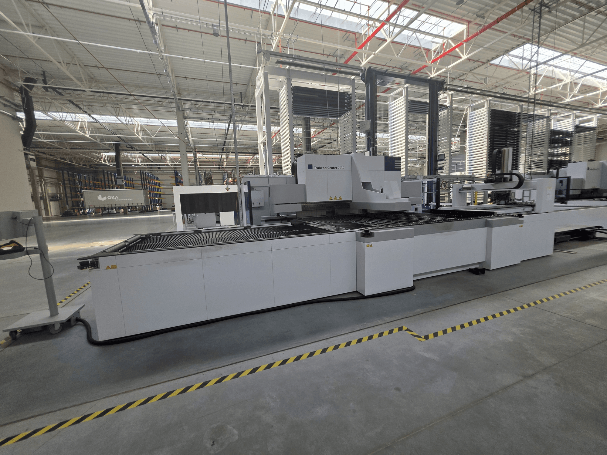 Plieuse TRUMPF TruBend Center 7030, vue de profil, mettant en évidence la zone de travail et les commandes dans un atelier spacieux.