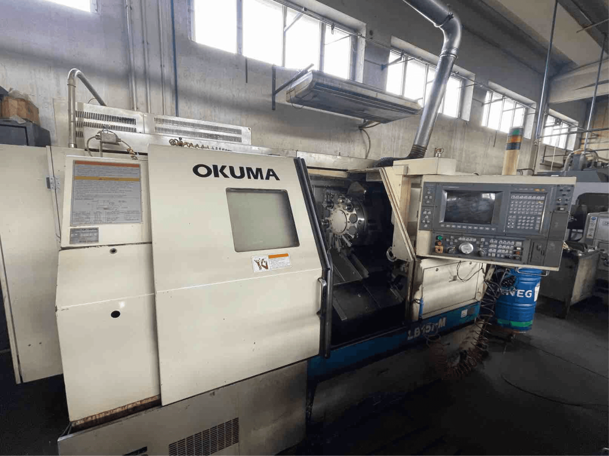 Tour horizontal Okuma LB15i-M, vue de face ; panneau de commande et zone des outils de coupe avec indicateurs détaillés.