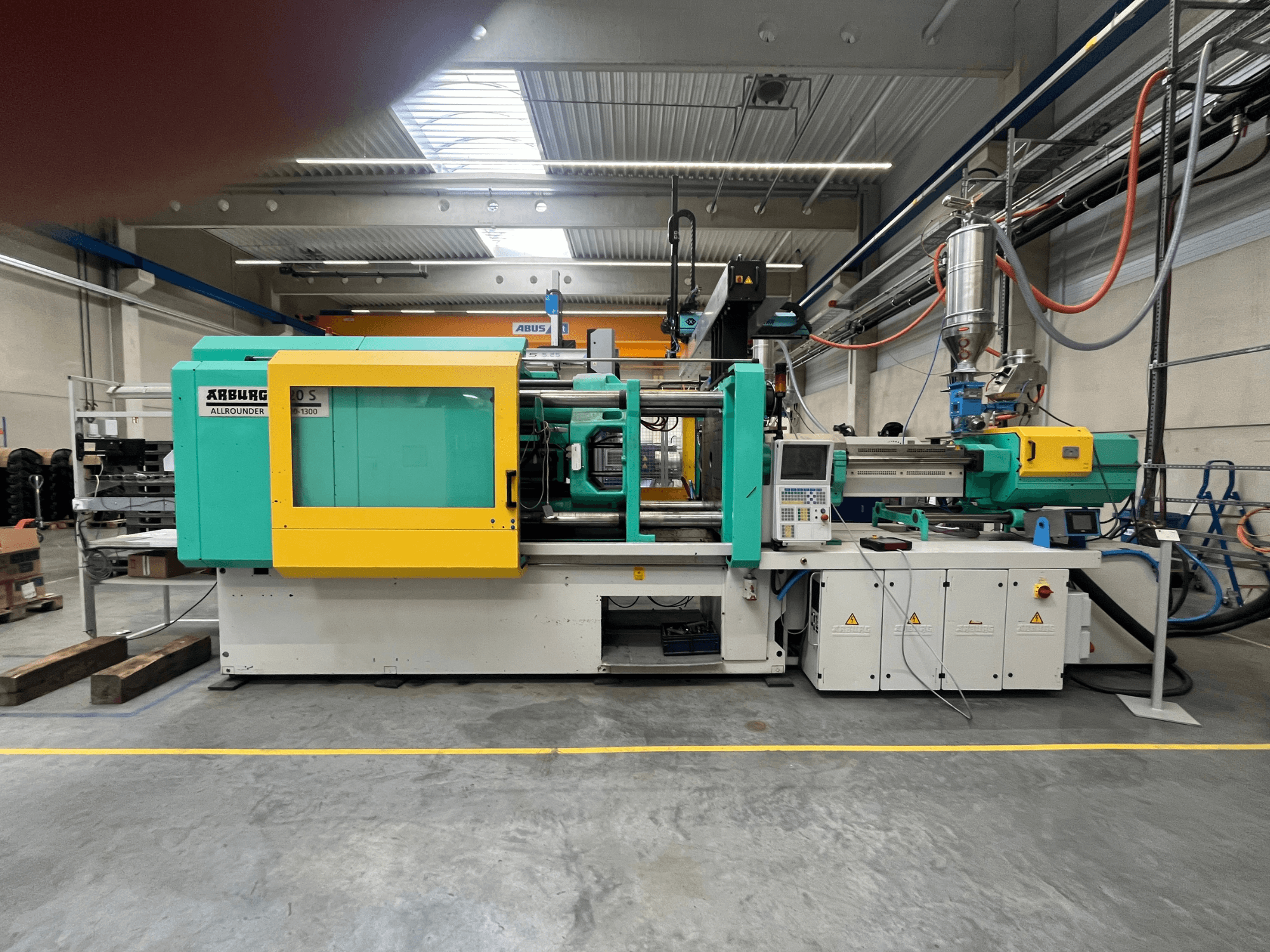ARBURG Allrounder 370S, machine de moulage par injection de plastique, vue de côté, avec boîtier vert et jaune, interface de commande visible.