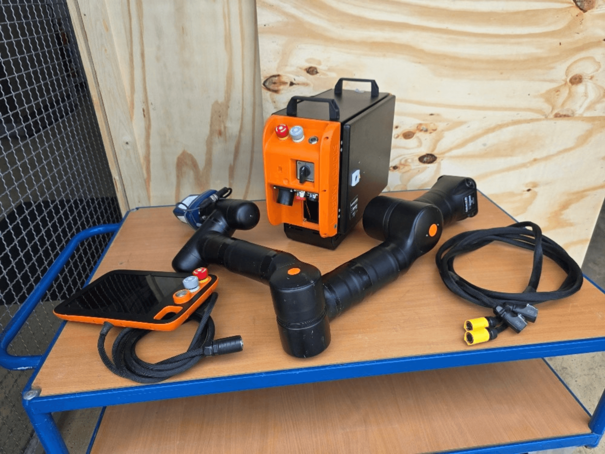 Robot collaboratif KASSOW ROBOTS KR810, vue de face, avec son contrôleur, ses câbles et ses connecteurs posés sur une table en bois.