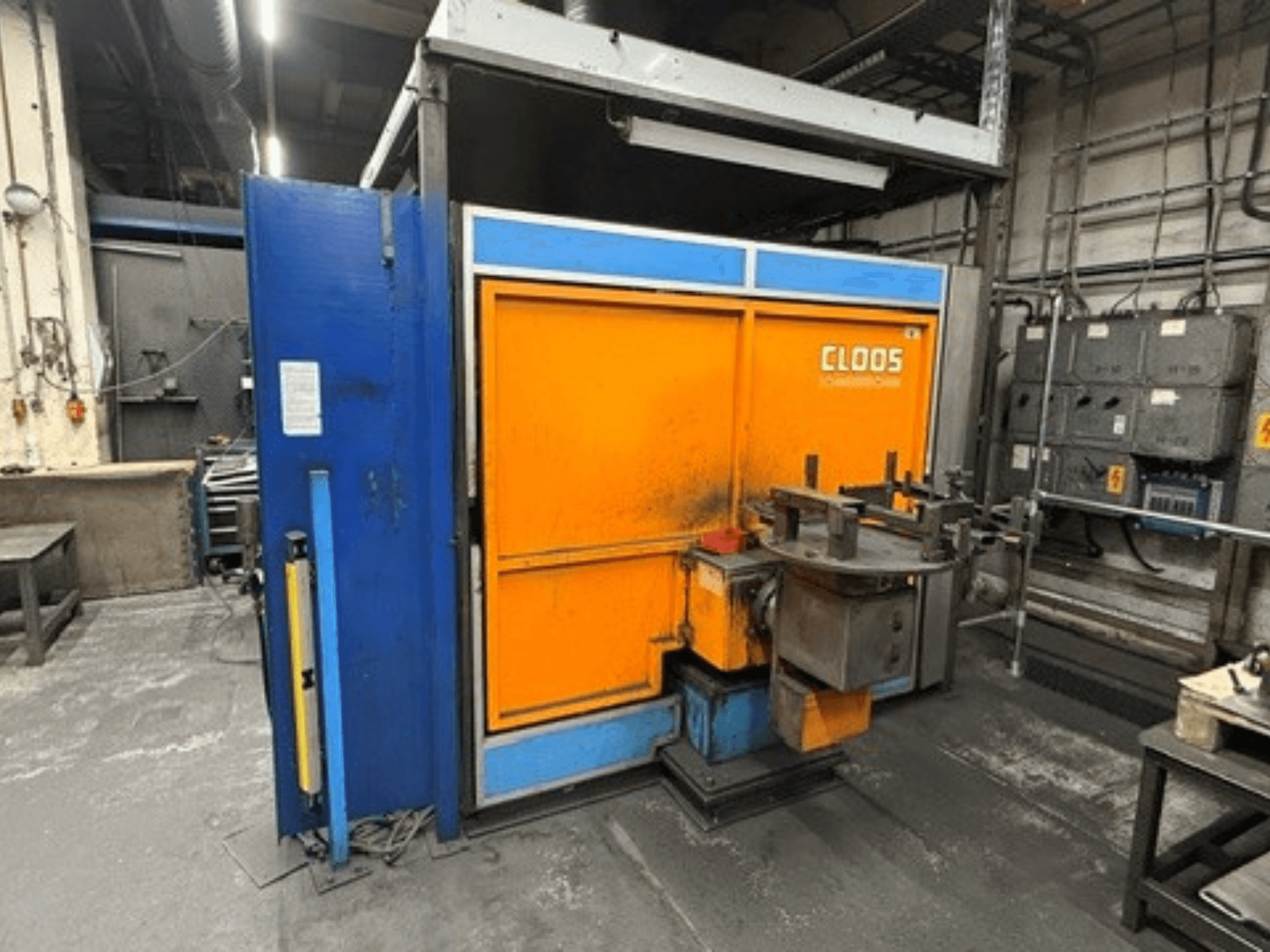 Robot de soudage CLOOS Romat 320 dans un atelier, vue de face montrant le boîtier orange et bleu avec le panneau de commande et les outils.